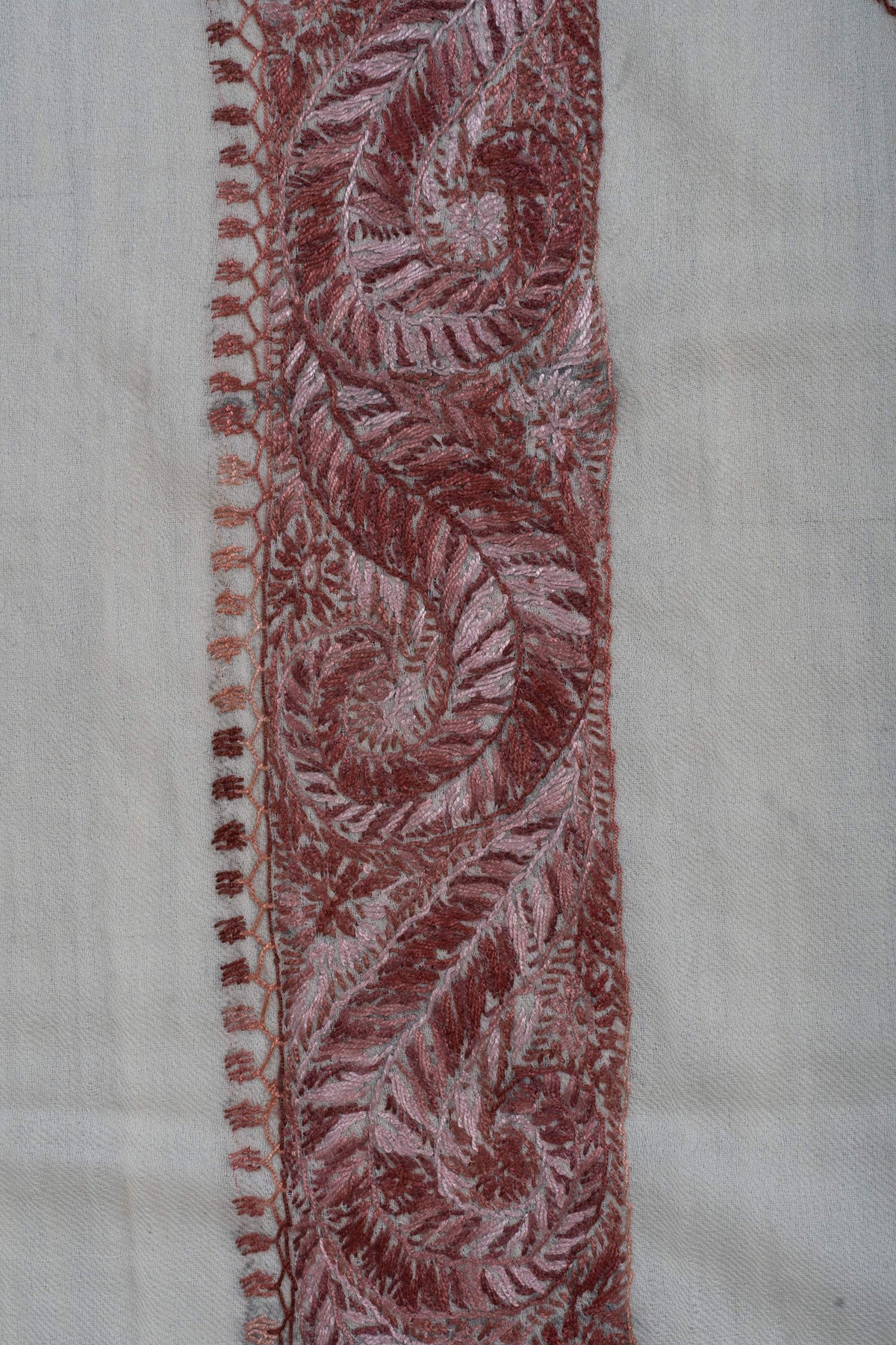 Close-up of curling dusty-rose paisleys and fine leaf edging along the ivory rumal's border