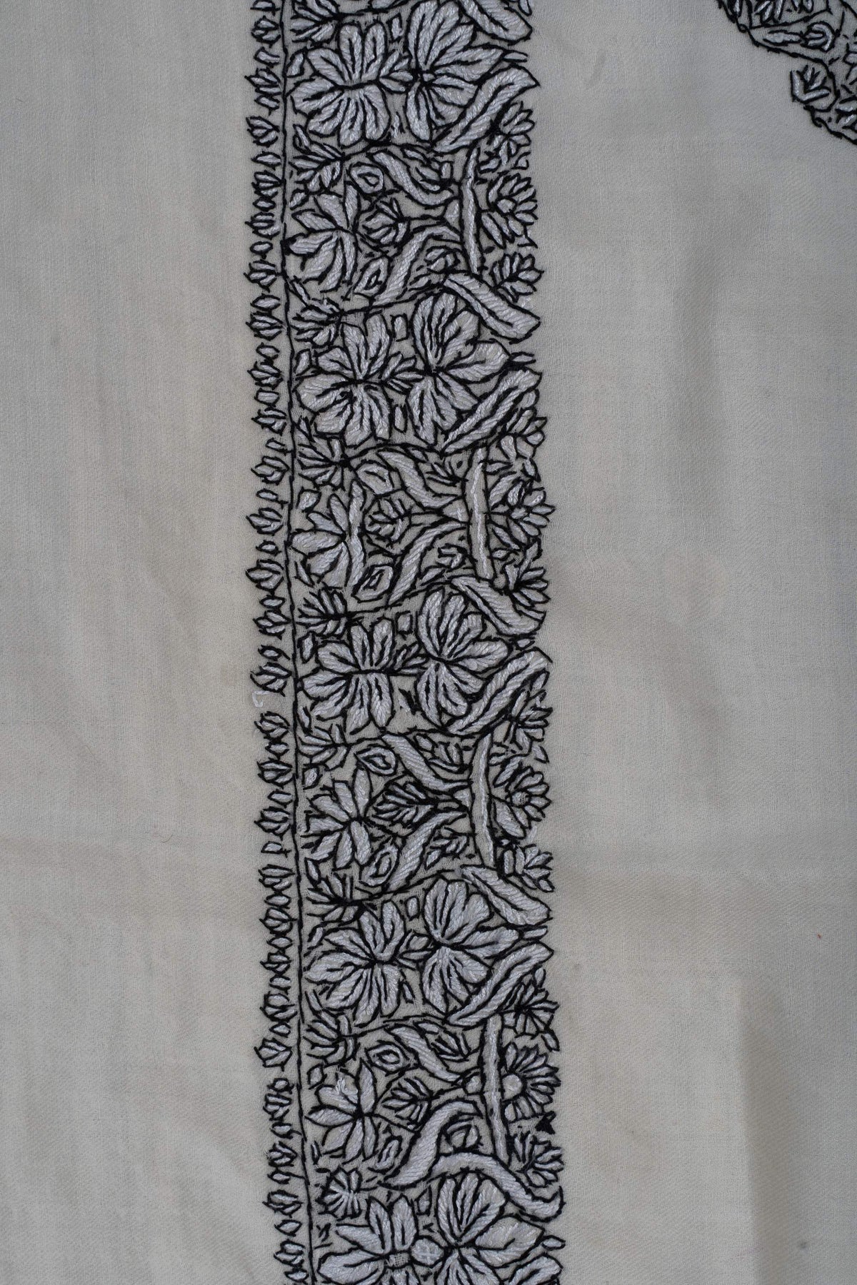 Close-up of a black Sozni rumal border with dense flowers, curling leaves and fine leafy edging