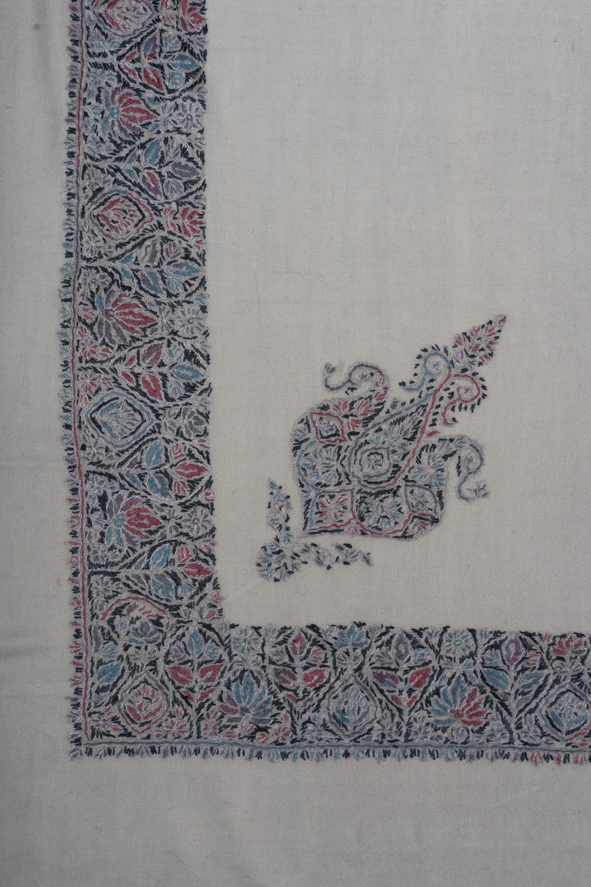 Ivory rumal corner with a dense rose-blue floral border and a smaller ornamental motif