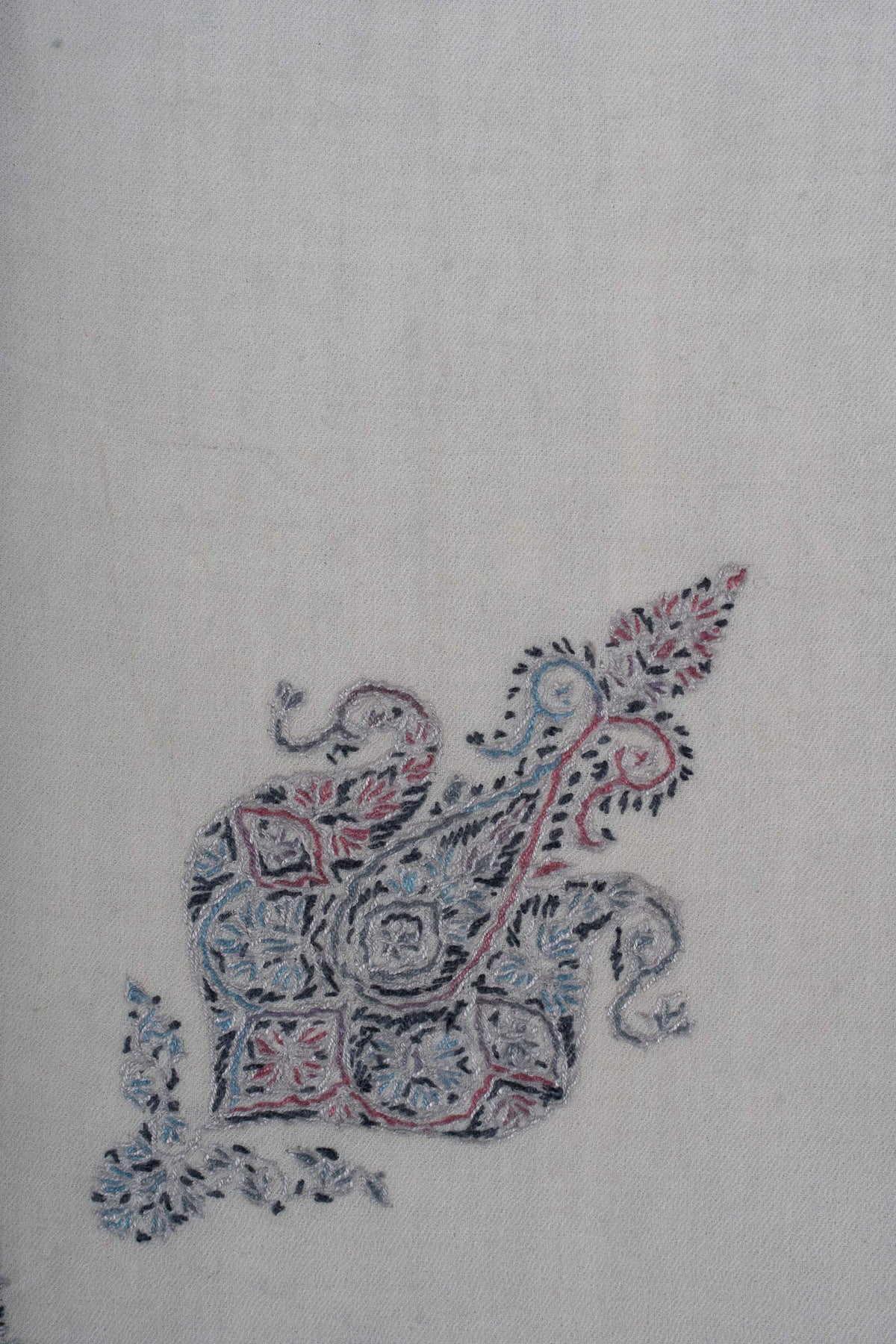 Close-up of the smaller curled motif with rose and blue flowers outlined in charcoal thread