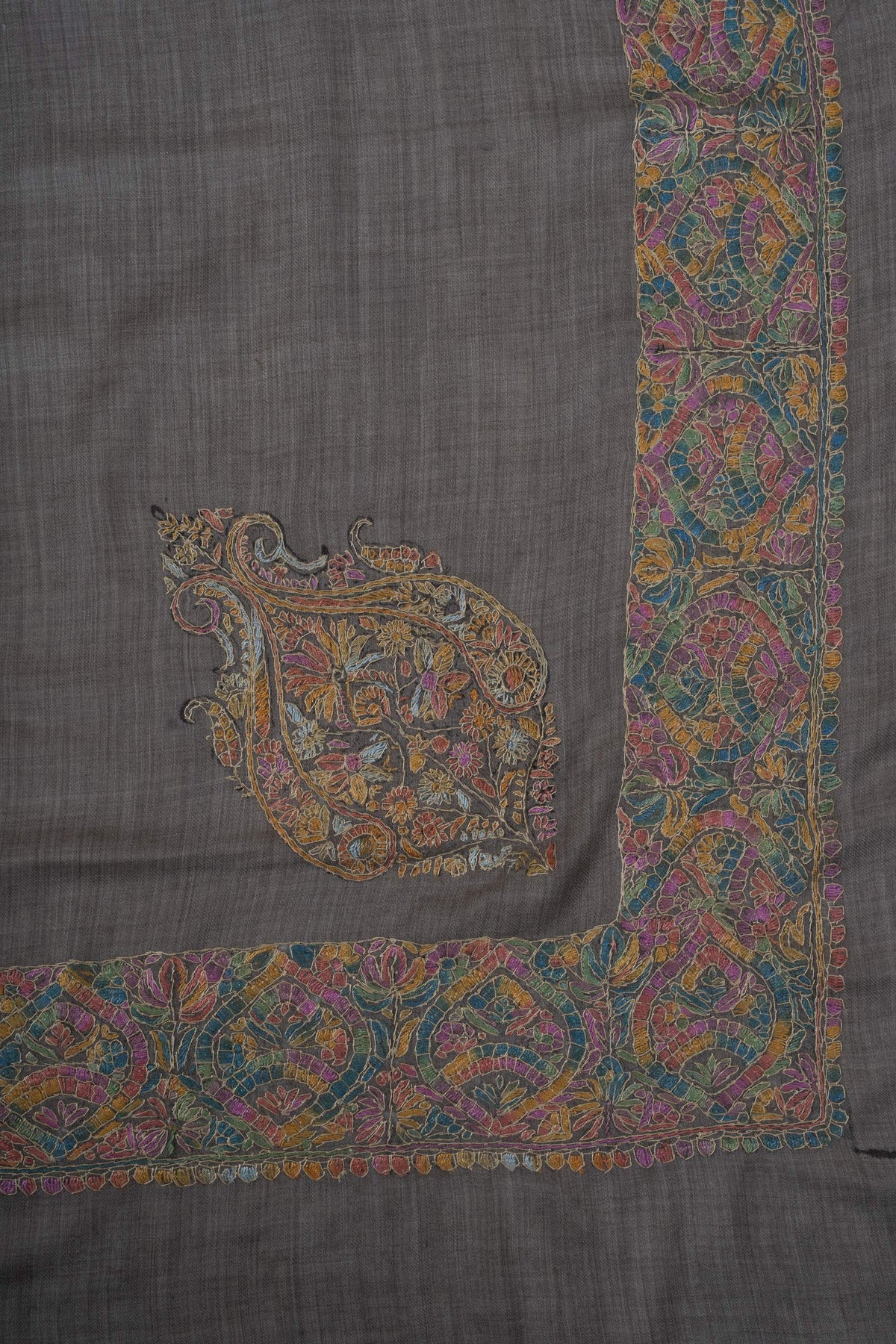 Corner of a charcoal Merino wool rumal with an ornate multicoloured Sozni motif and matching floral borders.