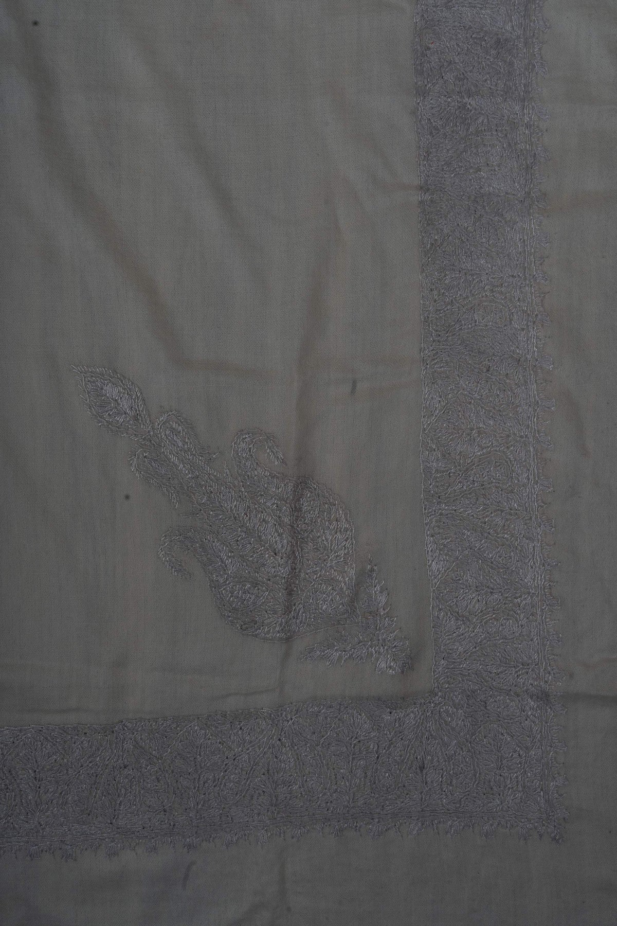 Corner of an ivory Merino wool rumal with an ornate silver-grey Sozni motif inside broad floral borders.