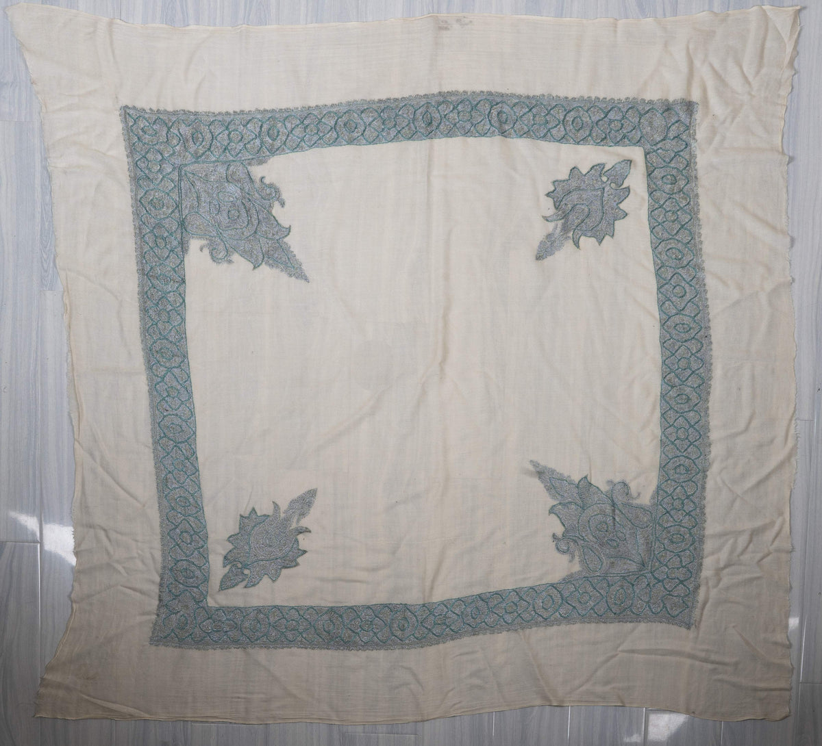 Ivory square rumal spread flat, showing a pale blue patterned border and four pointed corner motifs around a plain centre.