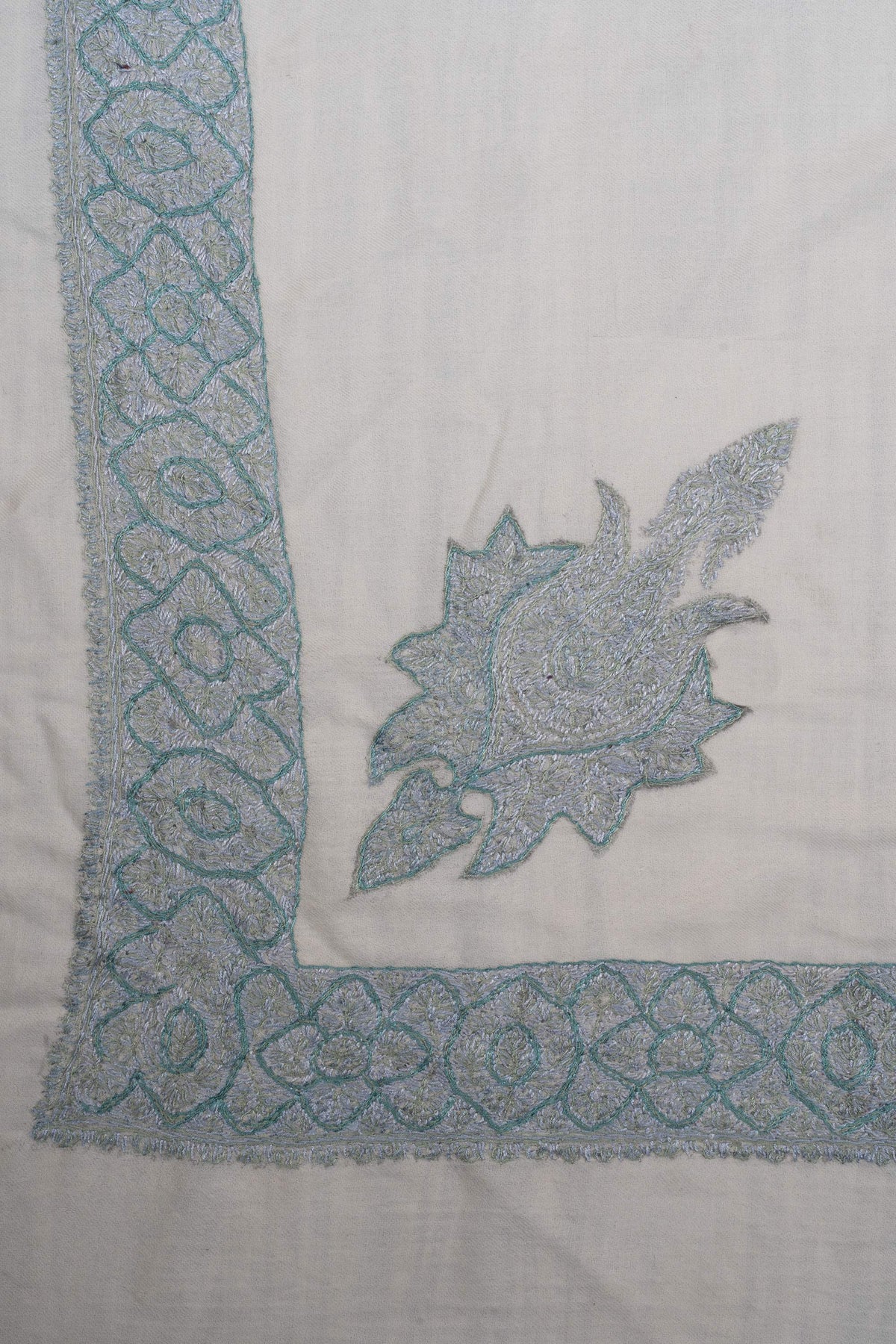 Ivory rumal corner with an icy-blue pointed floral motif and a border of interlaced flowers and medallions.