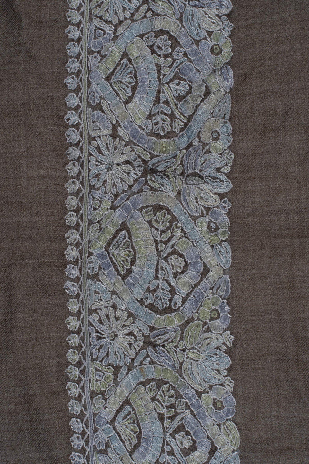 Detail of pale blue-grey Sozni medallions surrounded by flowers and tiny leaf edging along a taupe rumal border
