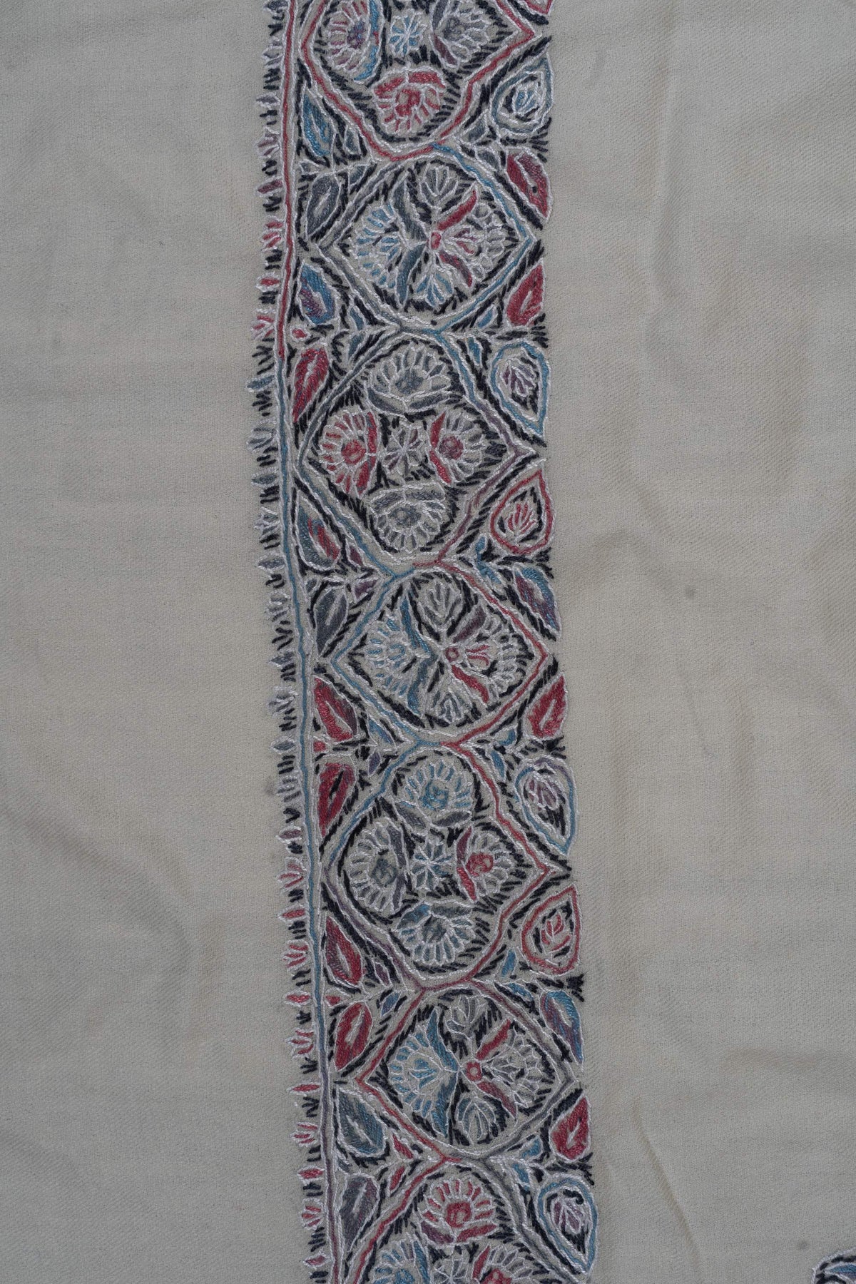 Close-up of blue, pink and slate floral medallions along the ivory rumal's embroidered border