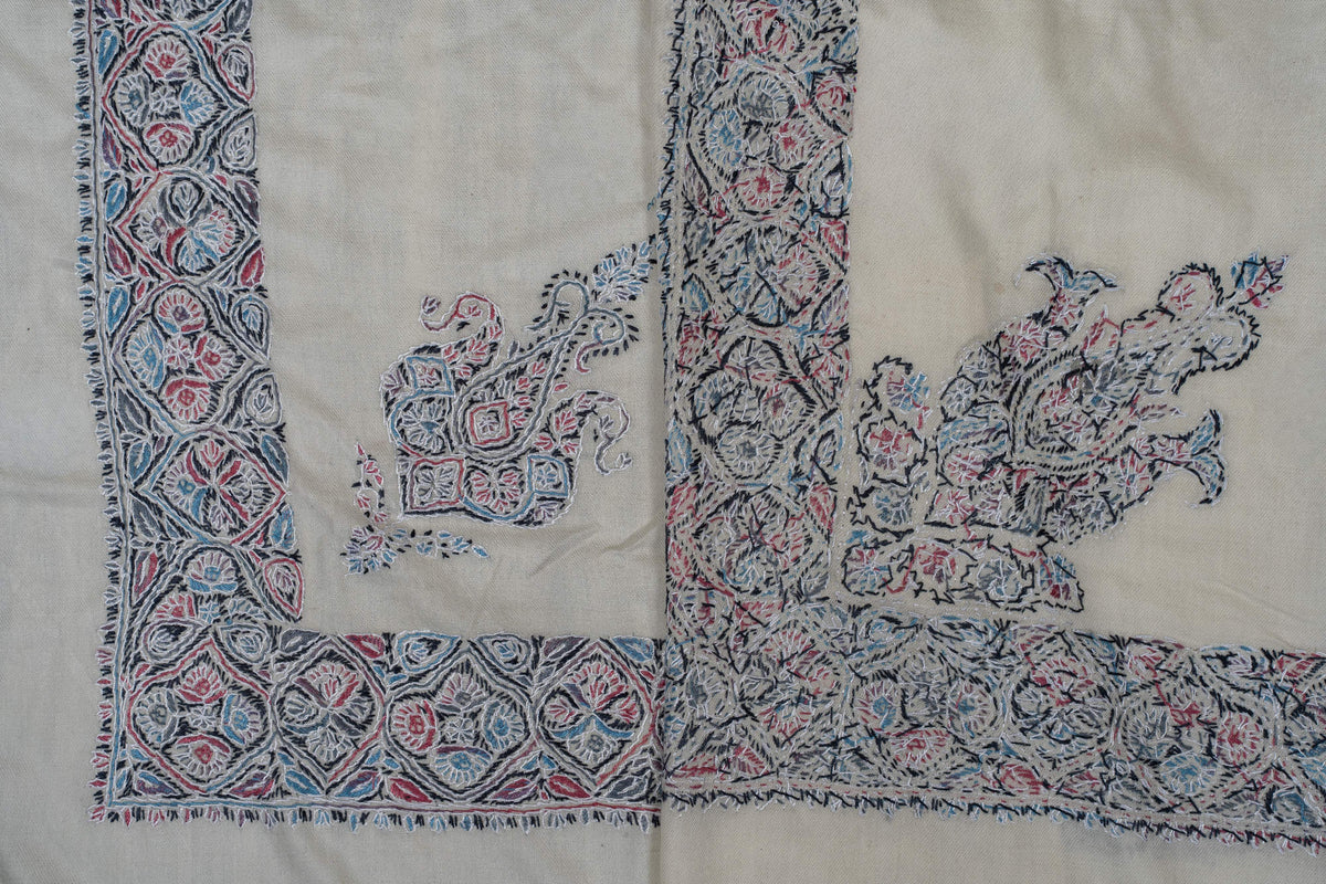 Overlapping ivory rumal corners showing the smaller motif beside the larger floral corner design