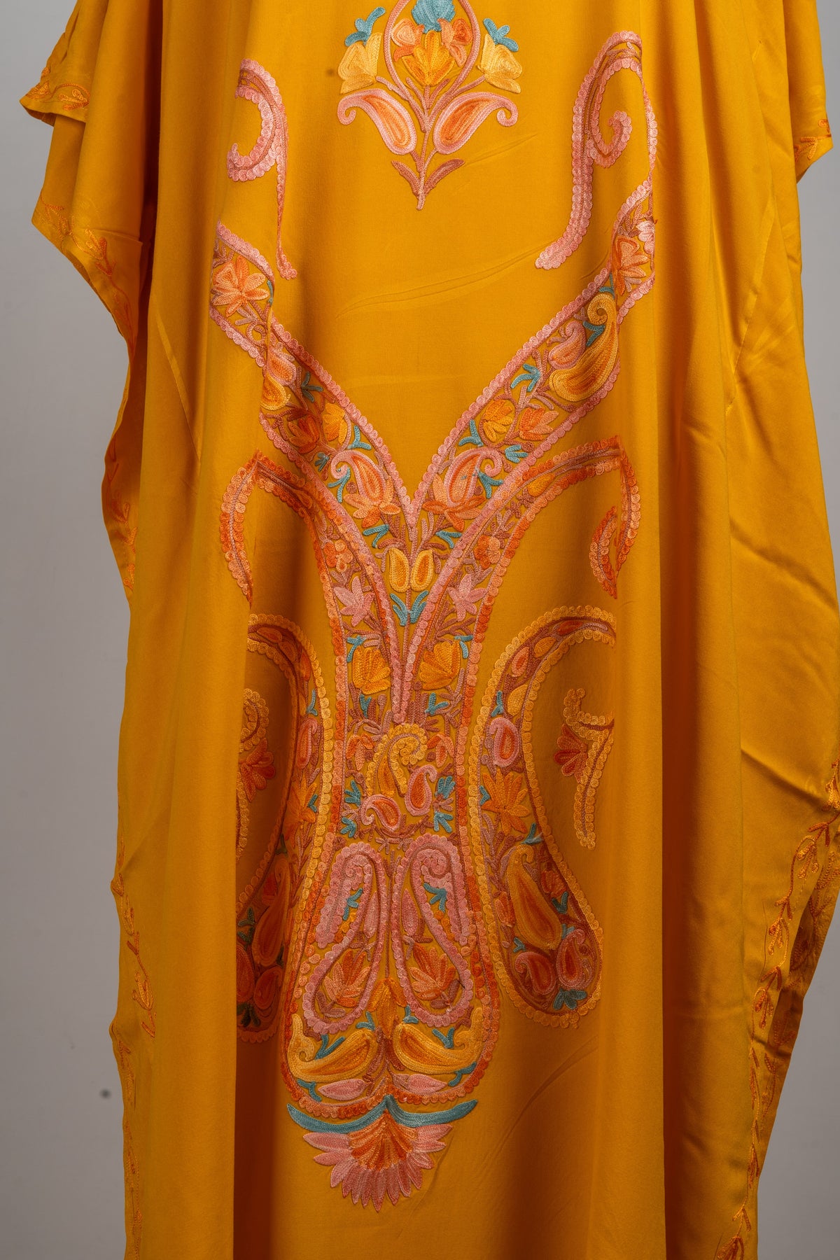 Close-up of the long central kaftan embroidery with paired peach paisley curves, small flowers and pale blue accents.