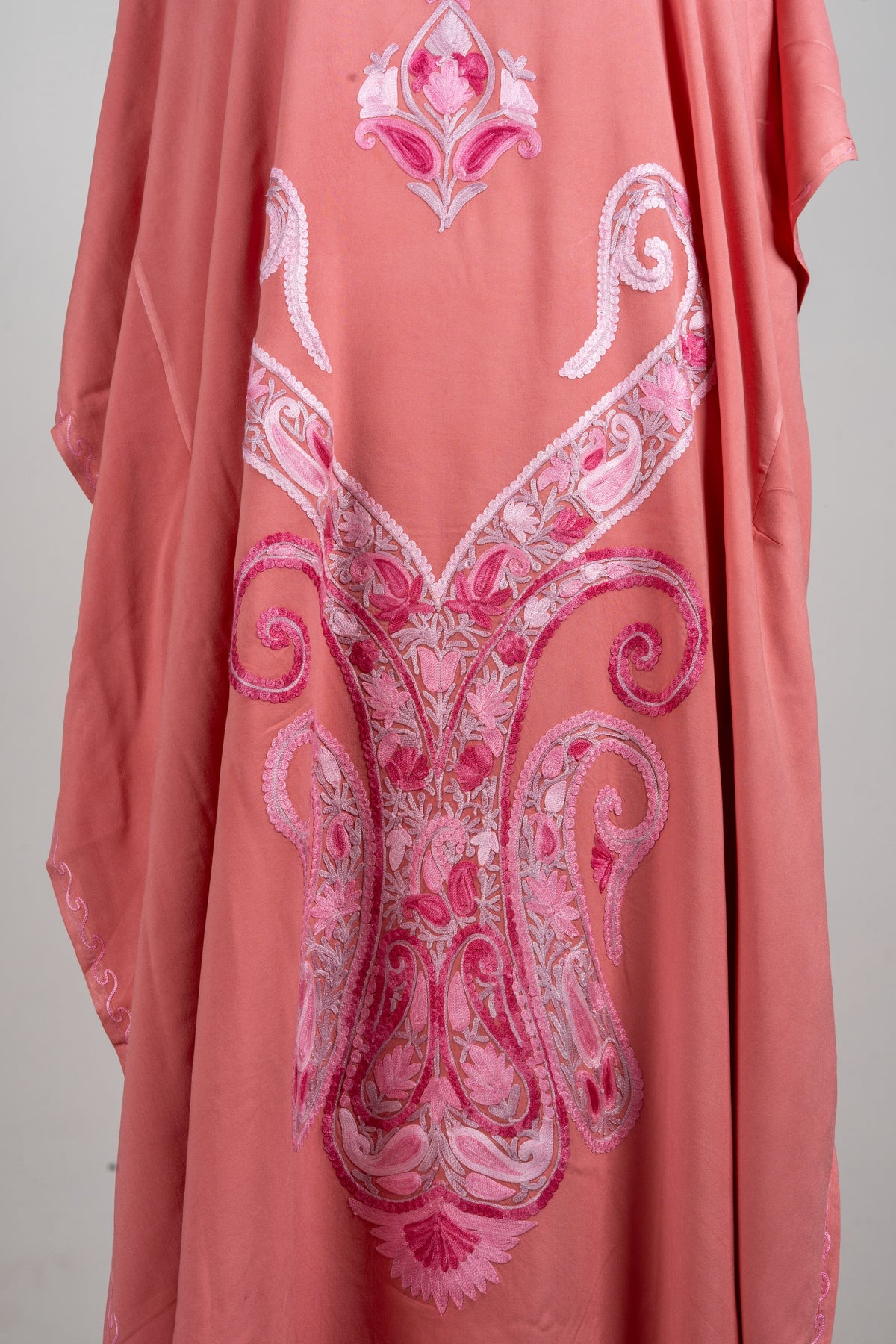 Close-up of the kaftan’s large symmetrical front design, with curled blush-and-fuchsia paisleys and fine floral stitching