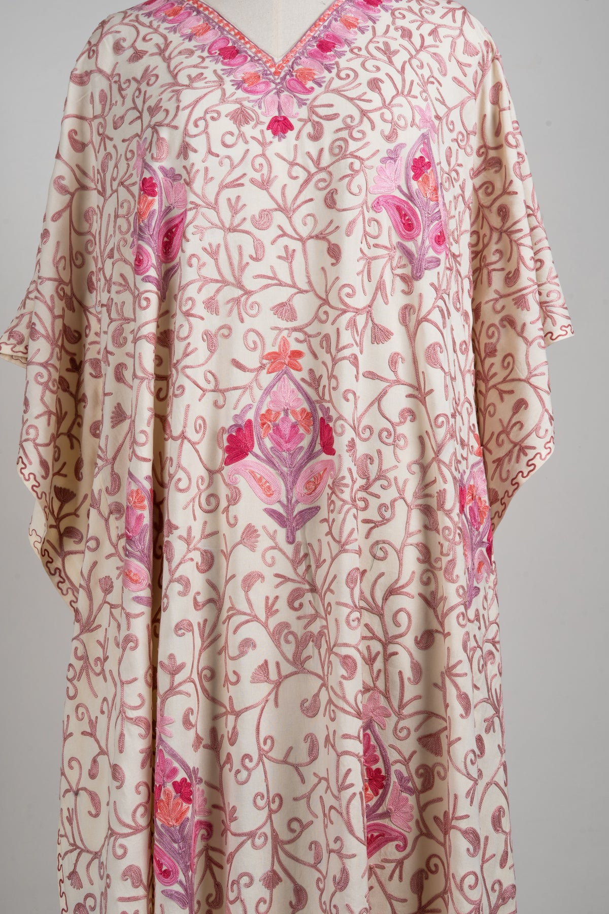 Front detail of a cream-beige kaftan with curling pink Aari vines and spaced larger floral medallions
