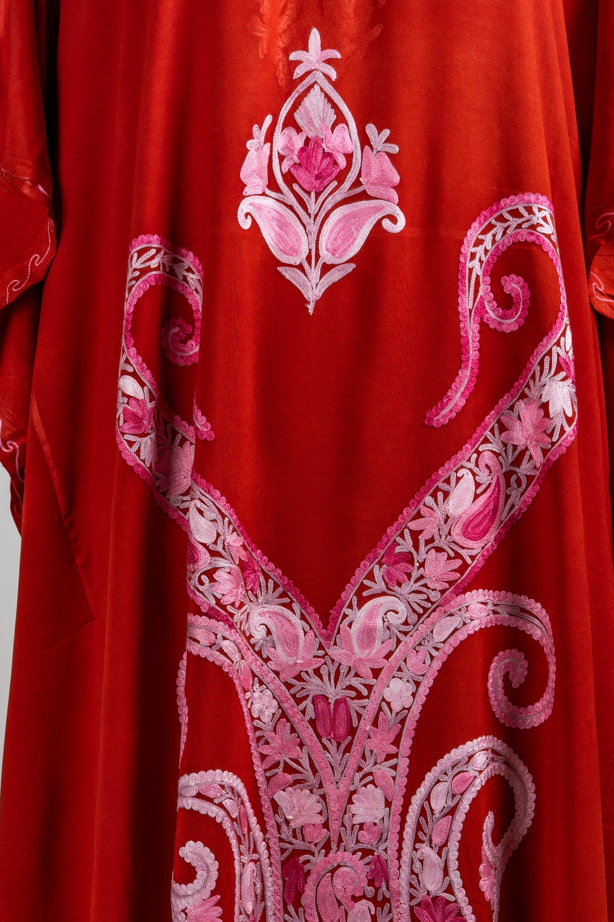 Close-up of the kaftan front with long pink paisley scrolls, delicate floral filling and a small motif above.