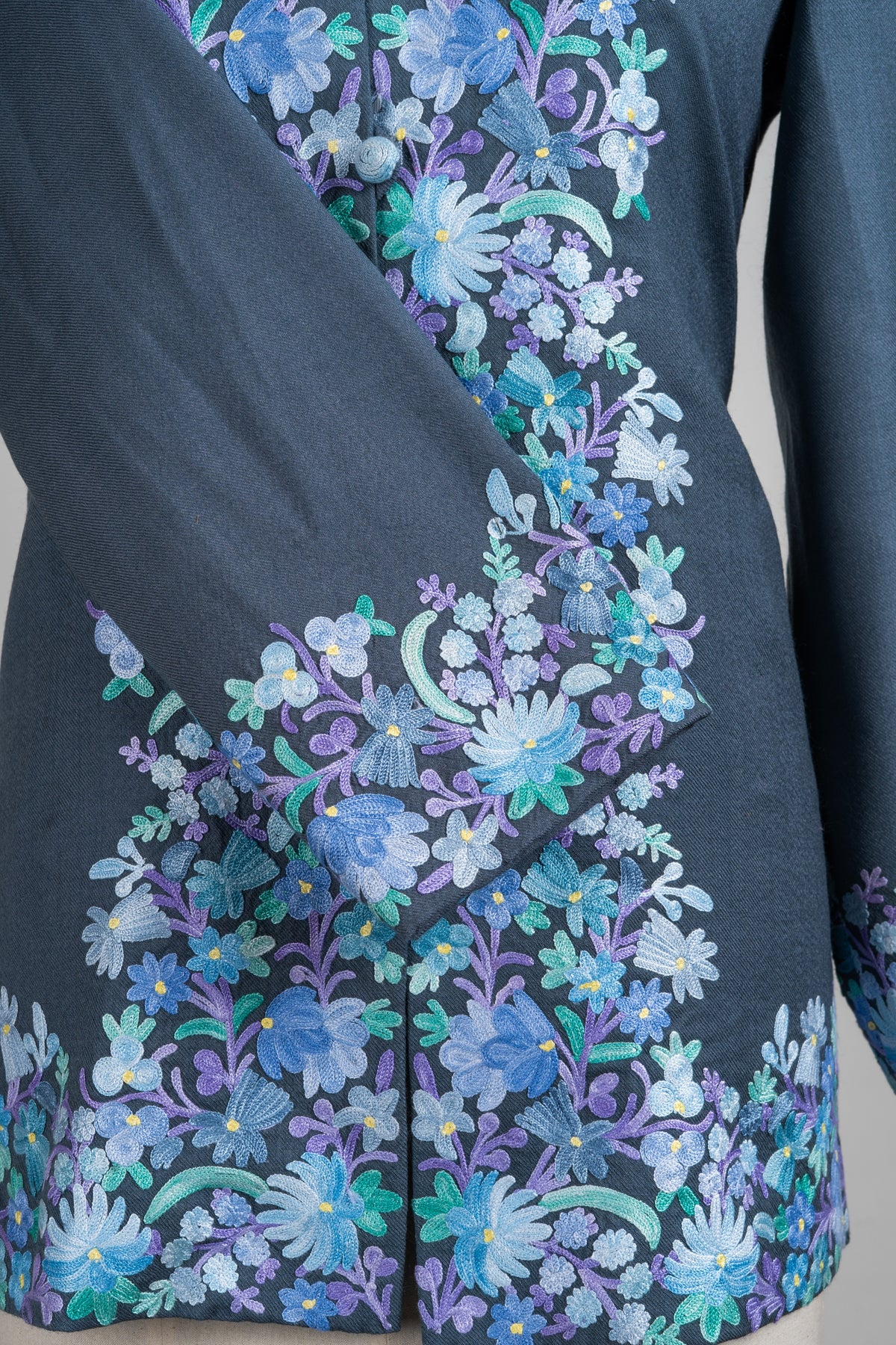 Close-up of the jacket crossed cuff and lower front, showing dense pastel flowers above the embroidered hem.
