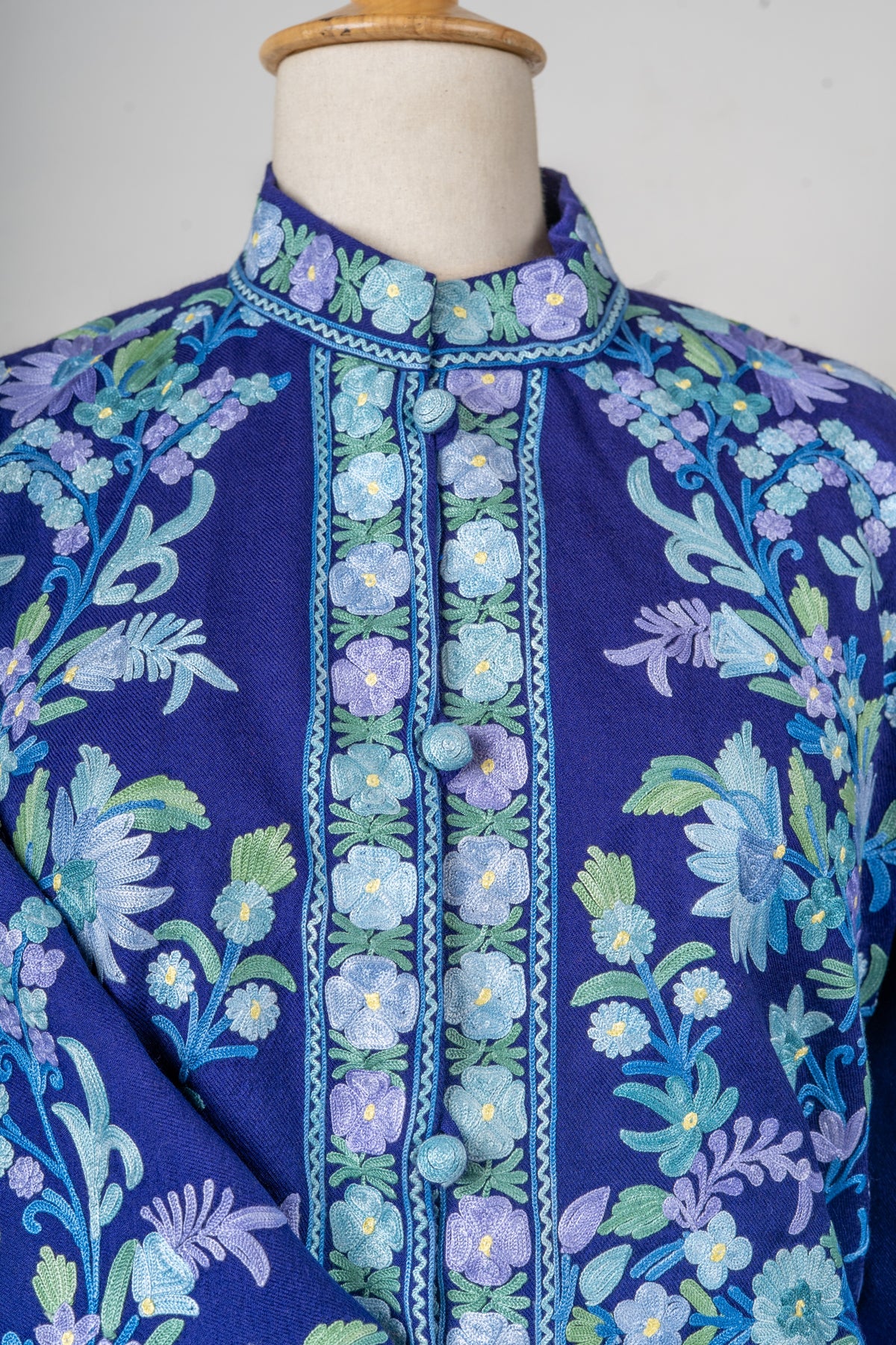 Detail of the indigo jacket’s embroidered stand collar, flower-bordered button placket and trailing floral vines
