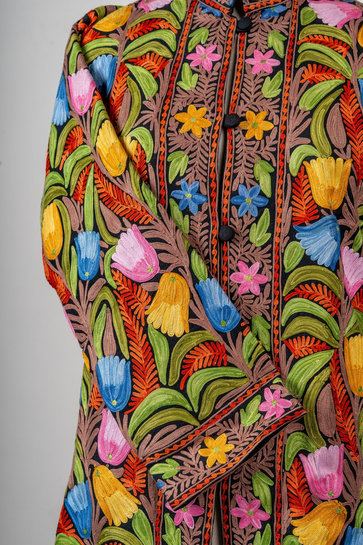 Detail of the jacket’s crossed sleeve and front, covered in colourful Aari tulips with small flowers along the cuff and placket