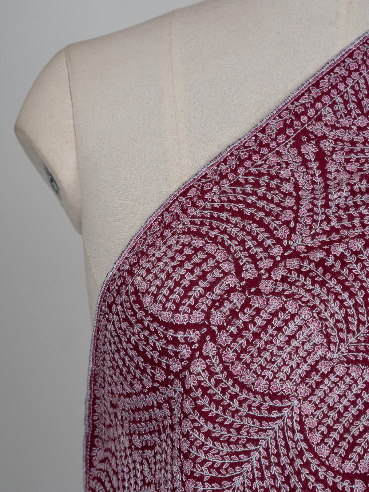 Shoulder close-up of the wine shawl, showing tiny pale flowers arranged in curved Sozni bands and circular medallions