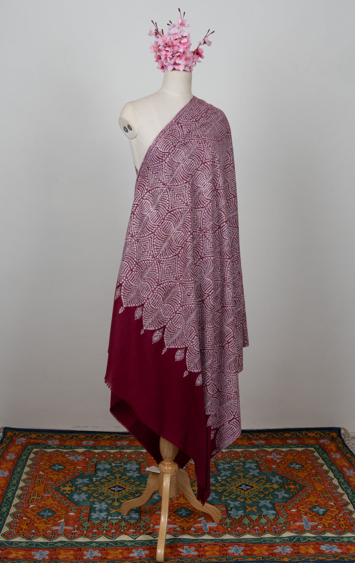 Full-length side view of the wine Pashmina shawl, with pale circular Sozni embroidery and a plain dark wine end