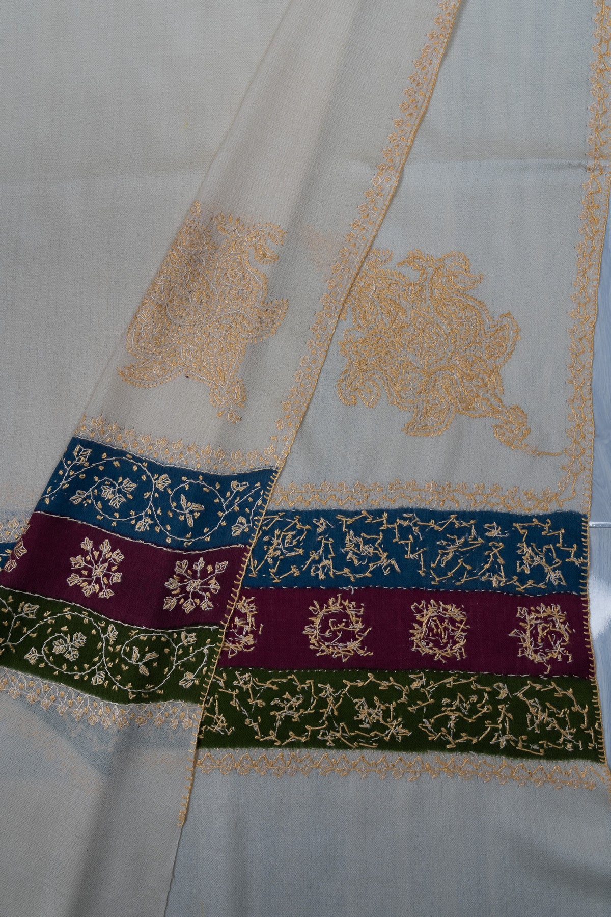 Folded ivory shawl corner showing both sides of pale golden motifs and multicoloured Sozni floral end bands