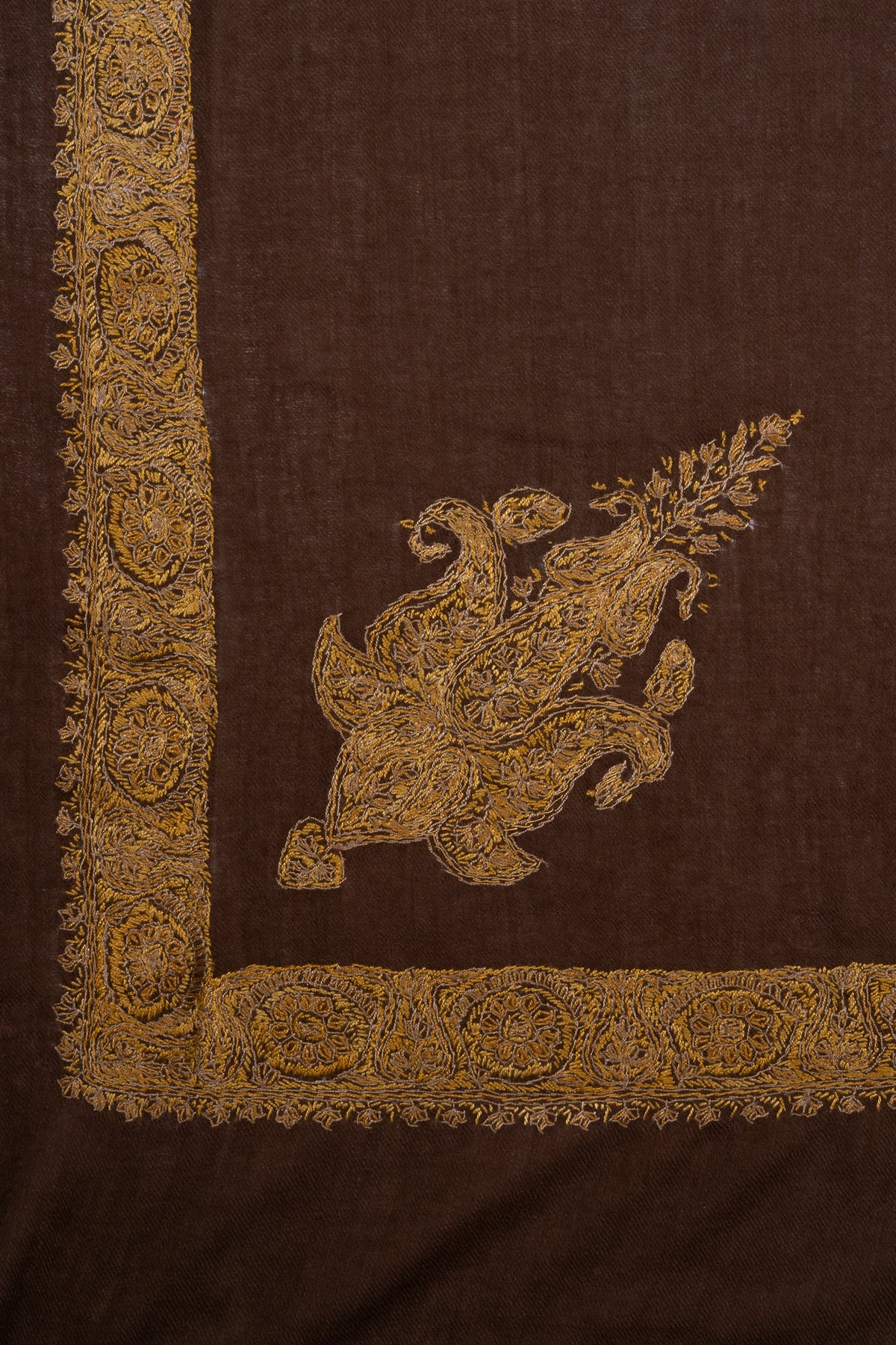 Flat corner detail of an umber-brown rumal with a golden floral border and a separate ornate paisley motif