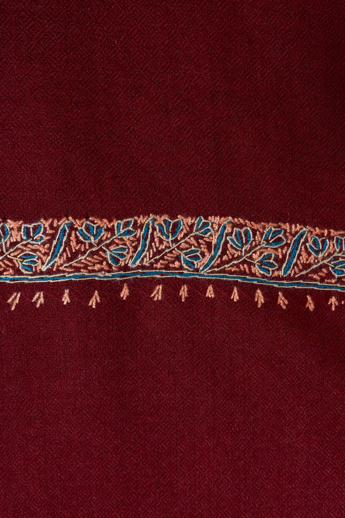 Close-up of the maroon shawl's teal leaf border with beige stems and small stitched accents
