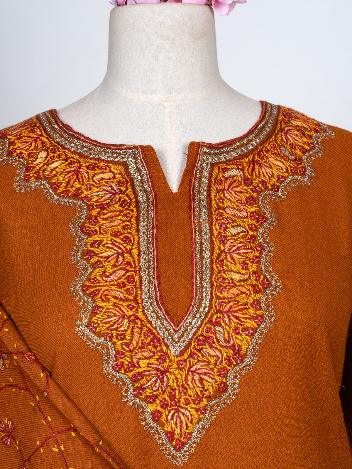 Close-up of a burnt-orange pheran neckline with gold and red Sozni leaves inside a pale scalloped outline