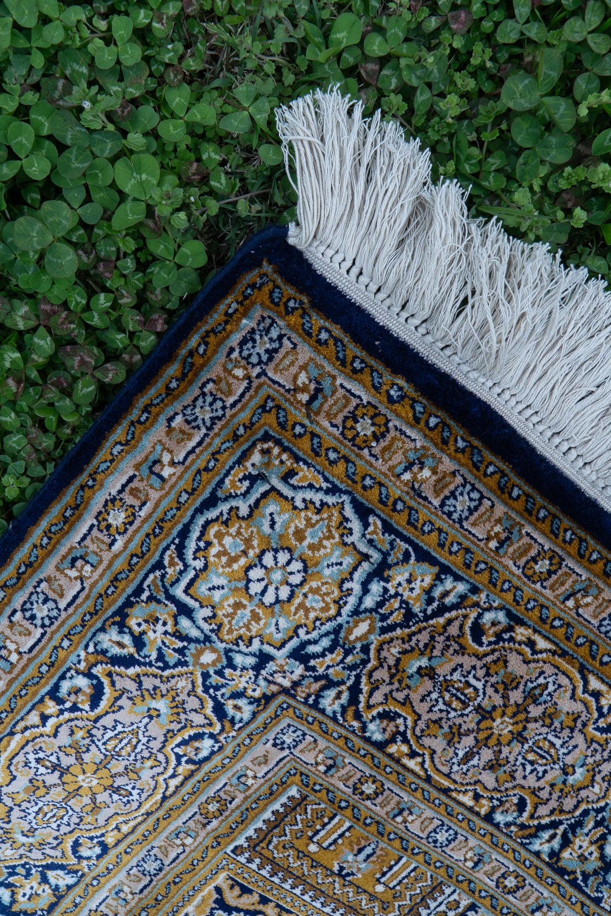 Carpet corner with gold and cream floral motifs on navy borders and white fringe
