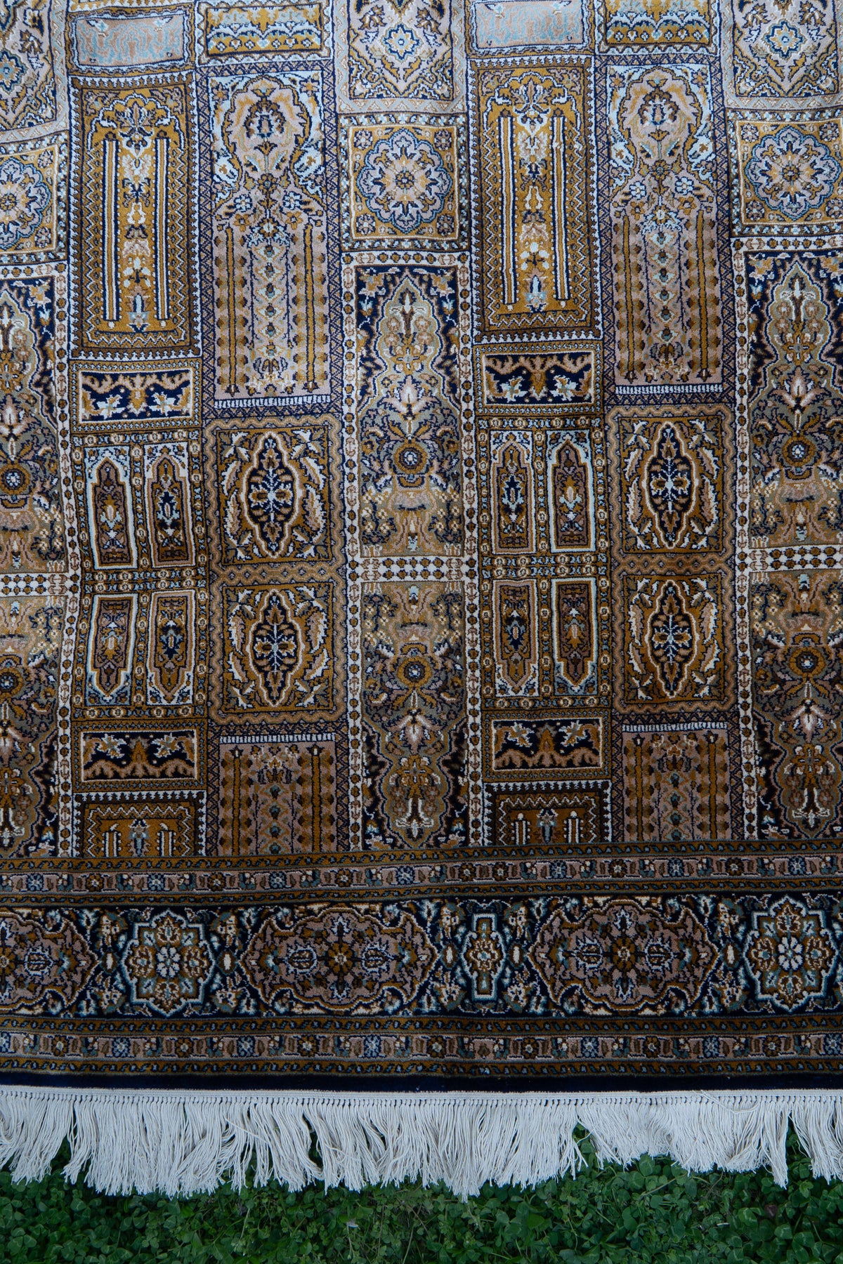 Lower section of the panel-patterned carpet with a broad floral border and white fringe