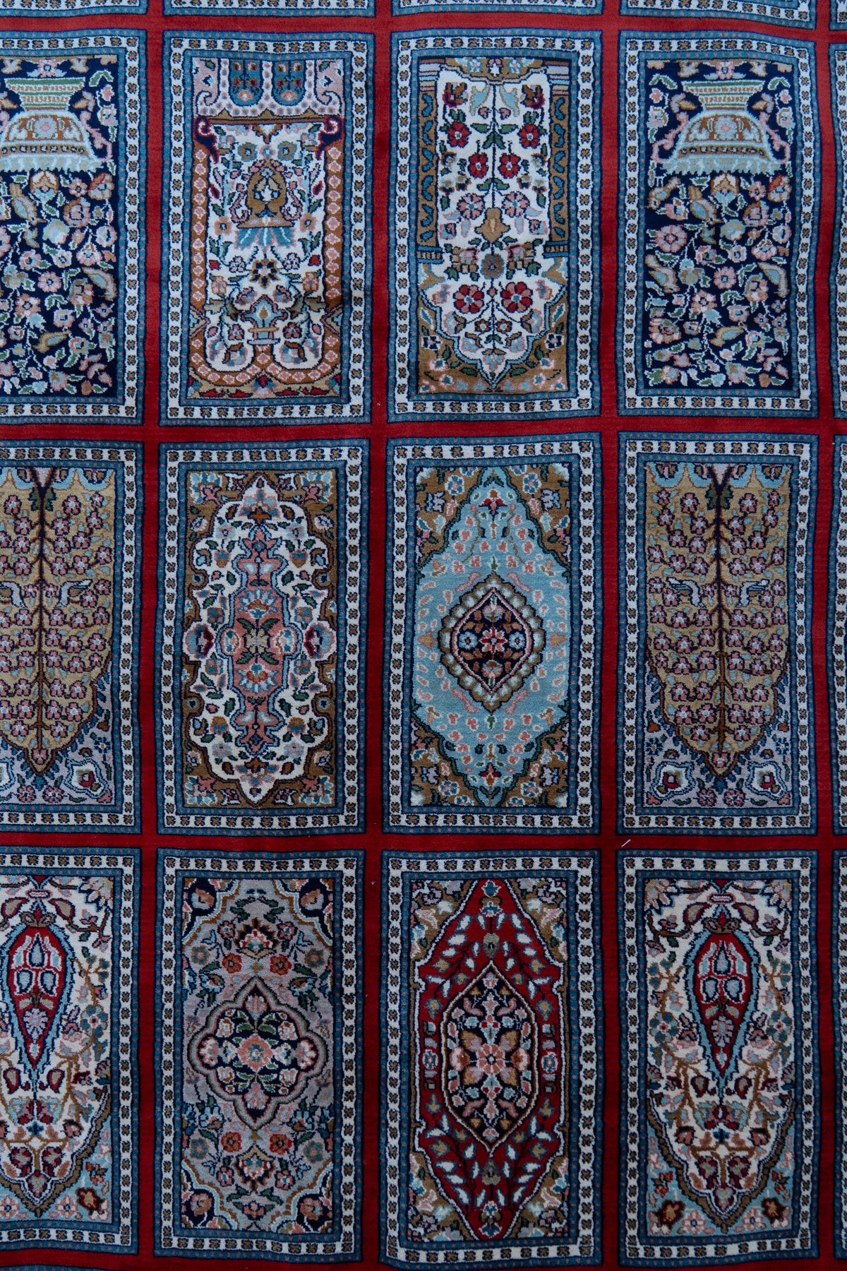 Close-up of rows of floral and geometric carpet panels separated by a crimson grid