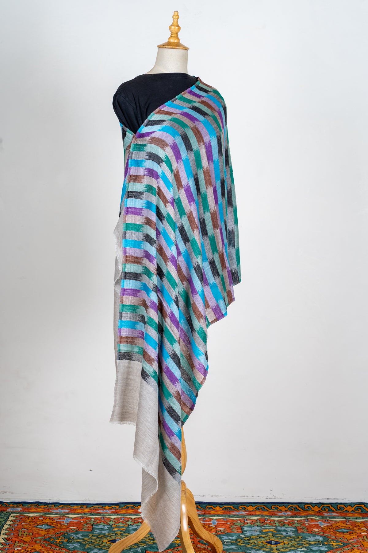 Full draped view of the multicoloured grid-pattern stole on a mannequin, with long plain pale-grey ends.