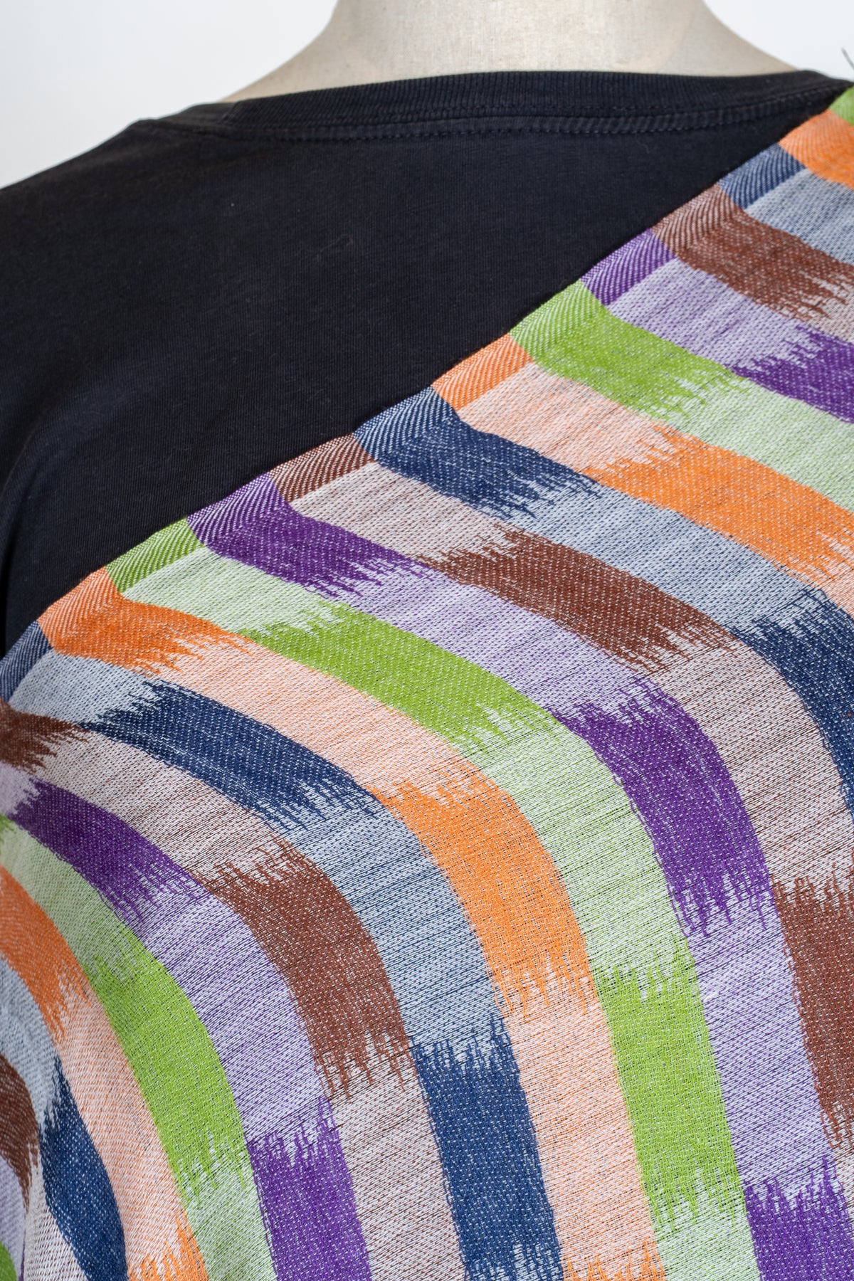 Close-up of a stole across a mannequin's shoulder, showing orange, green, purple and navy brushstroke blocks on a pale ground
