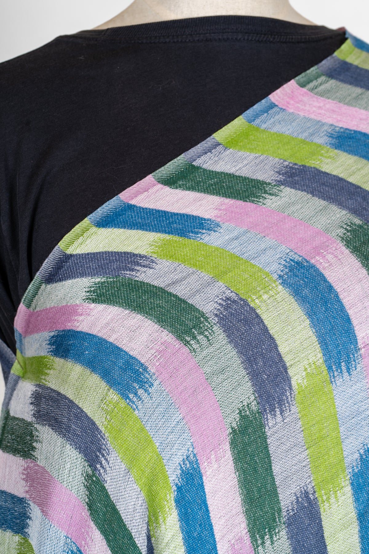 Close-up of pink, blue, grey and green brush-like blocks printed across the shoulder of a Merino wool stole