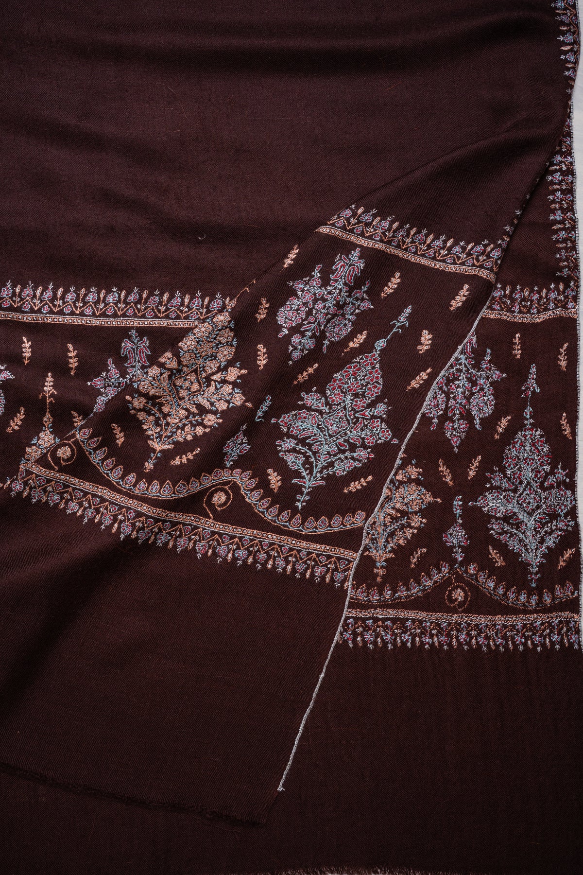 Chocolate-brown Pashmina shawl folded diagonally, showing overlapping embroidered floral end panels and narrow leafy borders.