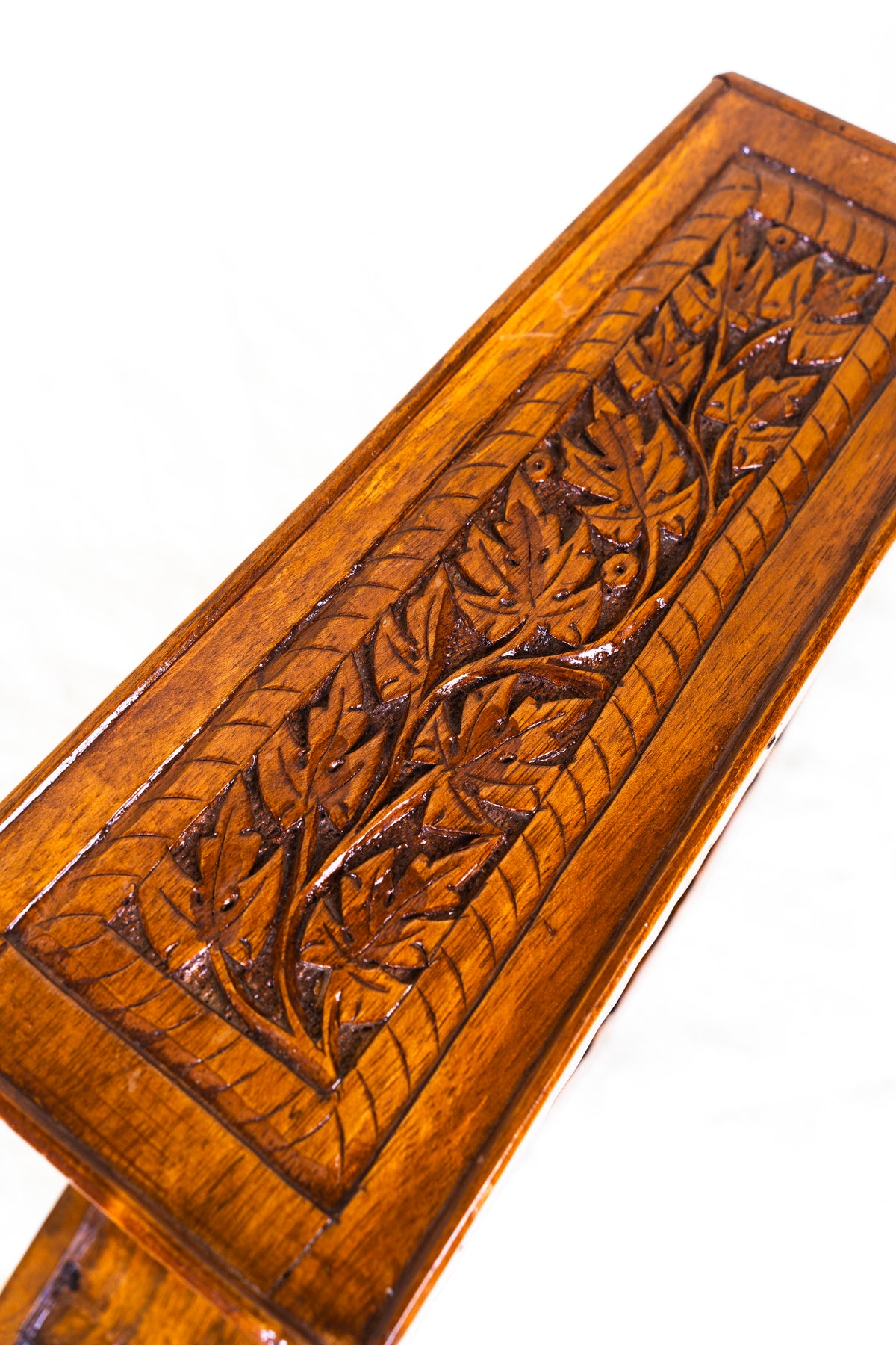 Close-up of leafy branch carvings inside the rectangular canopy panel of a walnut wood shikara model