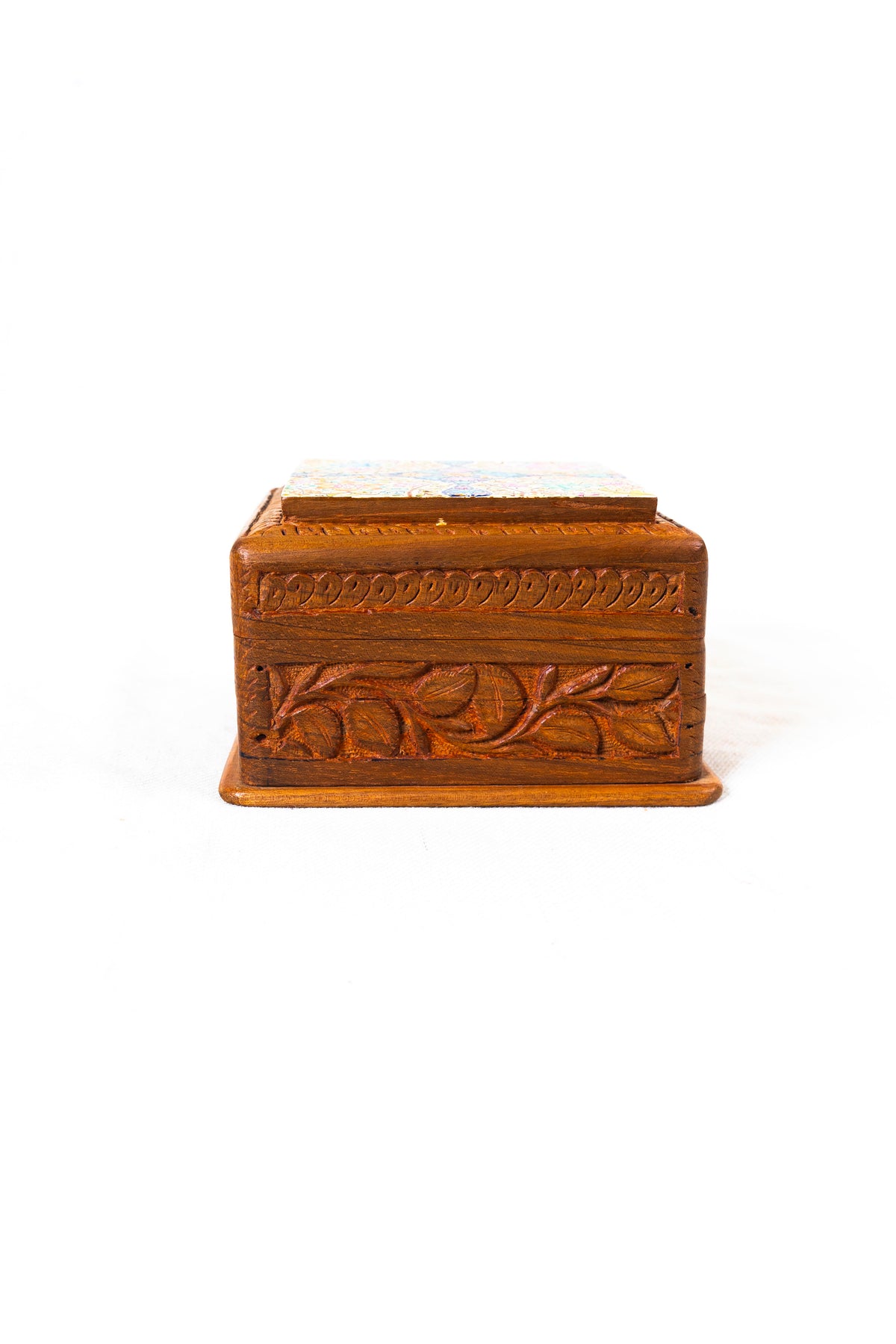 Side view of the walnut wood box with a carved leaf-and-vine panel beneath the raised lid.