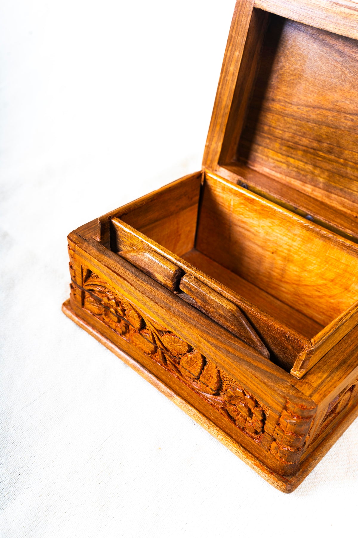 Close-up inside an open walnut wood box, showing the wood grain, inner wooden fittings and carved front edge