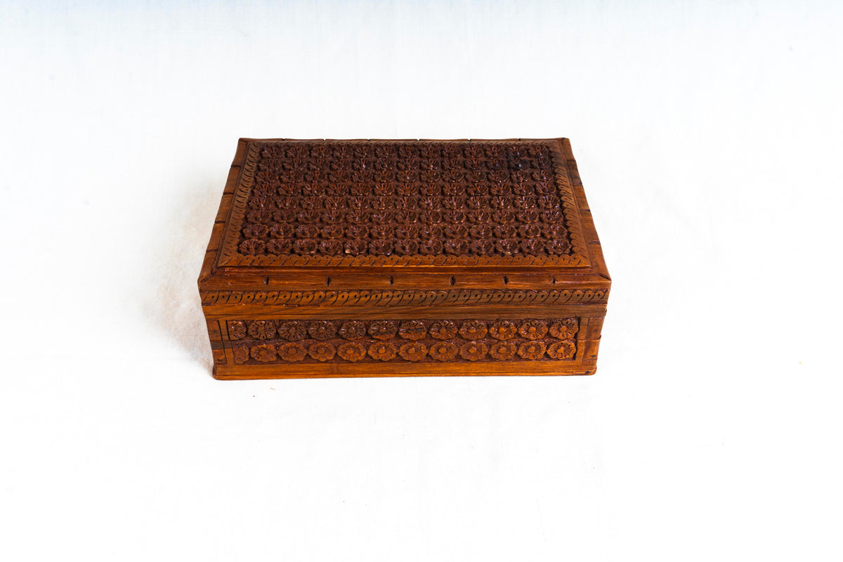 Front view of the closed walnut box with a carved floral lid and matching rectangular side panels