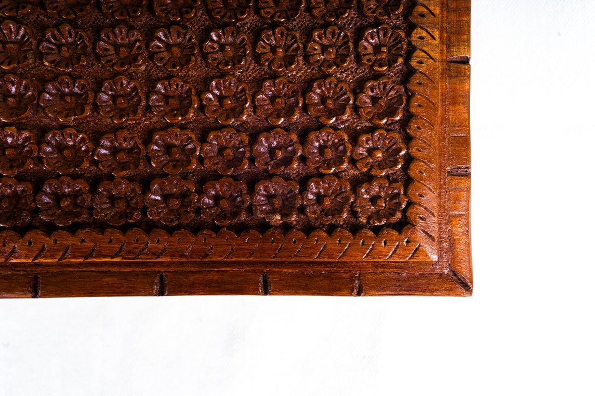 Close-up of the walnut box lid corner with deep flower carving and a narrow patterned border