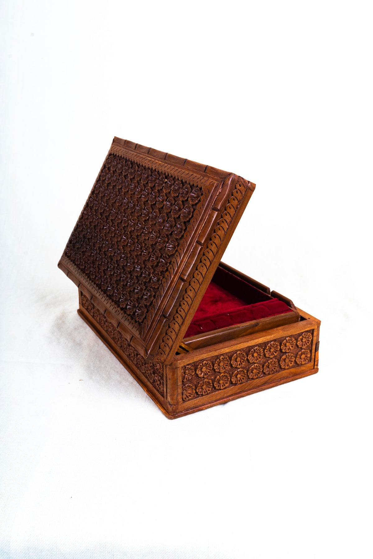 Angled view of the walnut box with the carved lid propped partly open and red lining visible inside