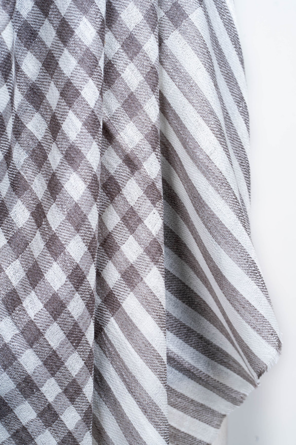 Close-up of the stole’s taupe and white checks transitioning into broad stripes at the hanging end.