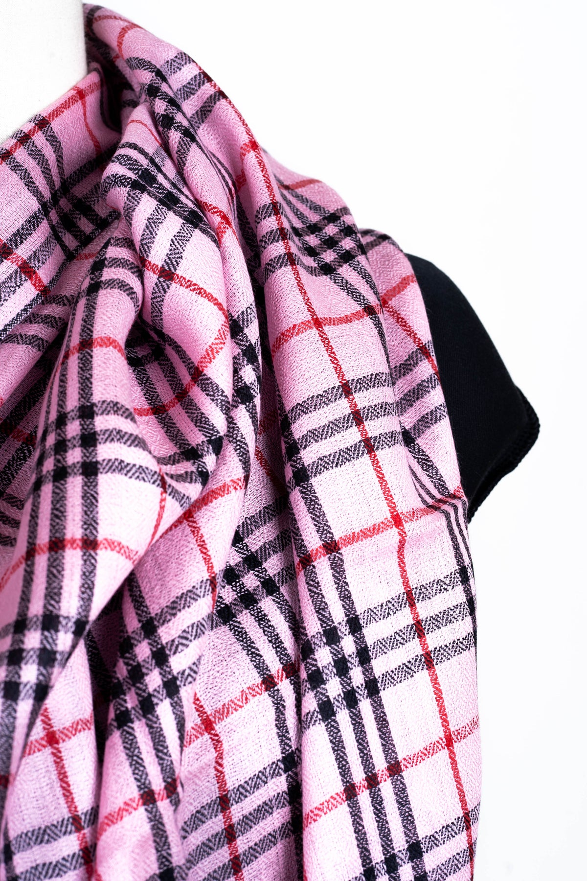 Close-up of the pink, black and red checked weave of a Merino wool stole draped across a mannequin