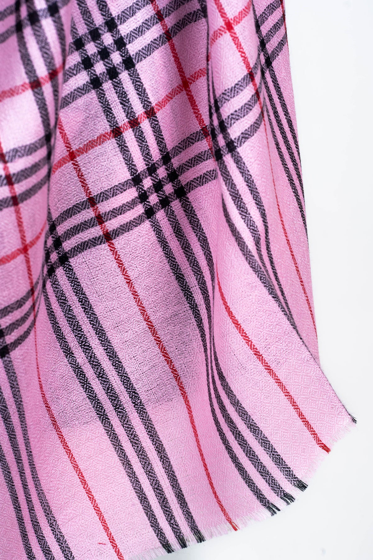Close-up of a pink stole end with black and red stripes continuing from the checked pattern to a short fringed edge