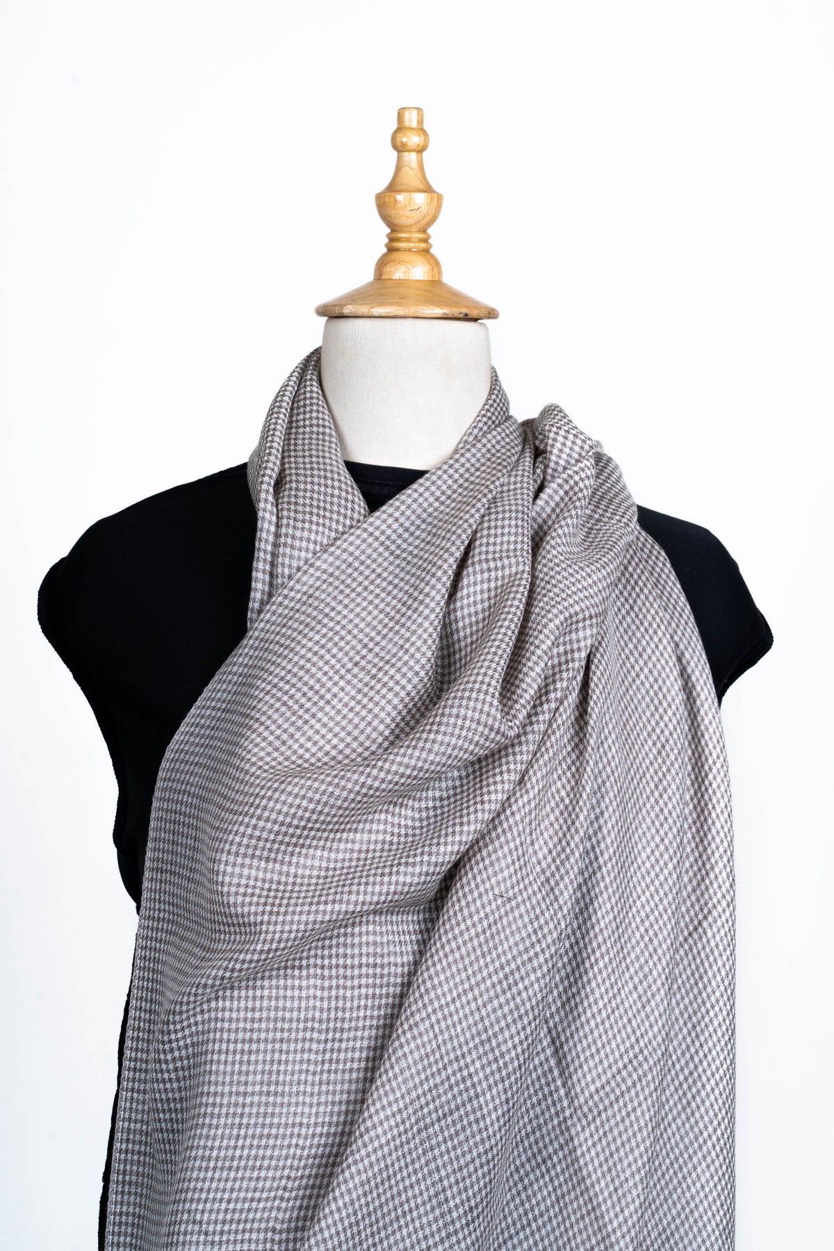 Grey and ivory checked stole swept across a mannequin chest and gathered over one shoulder.