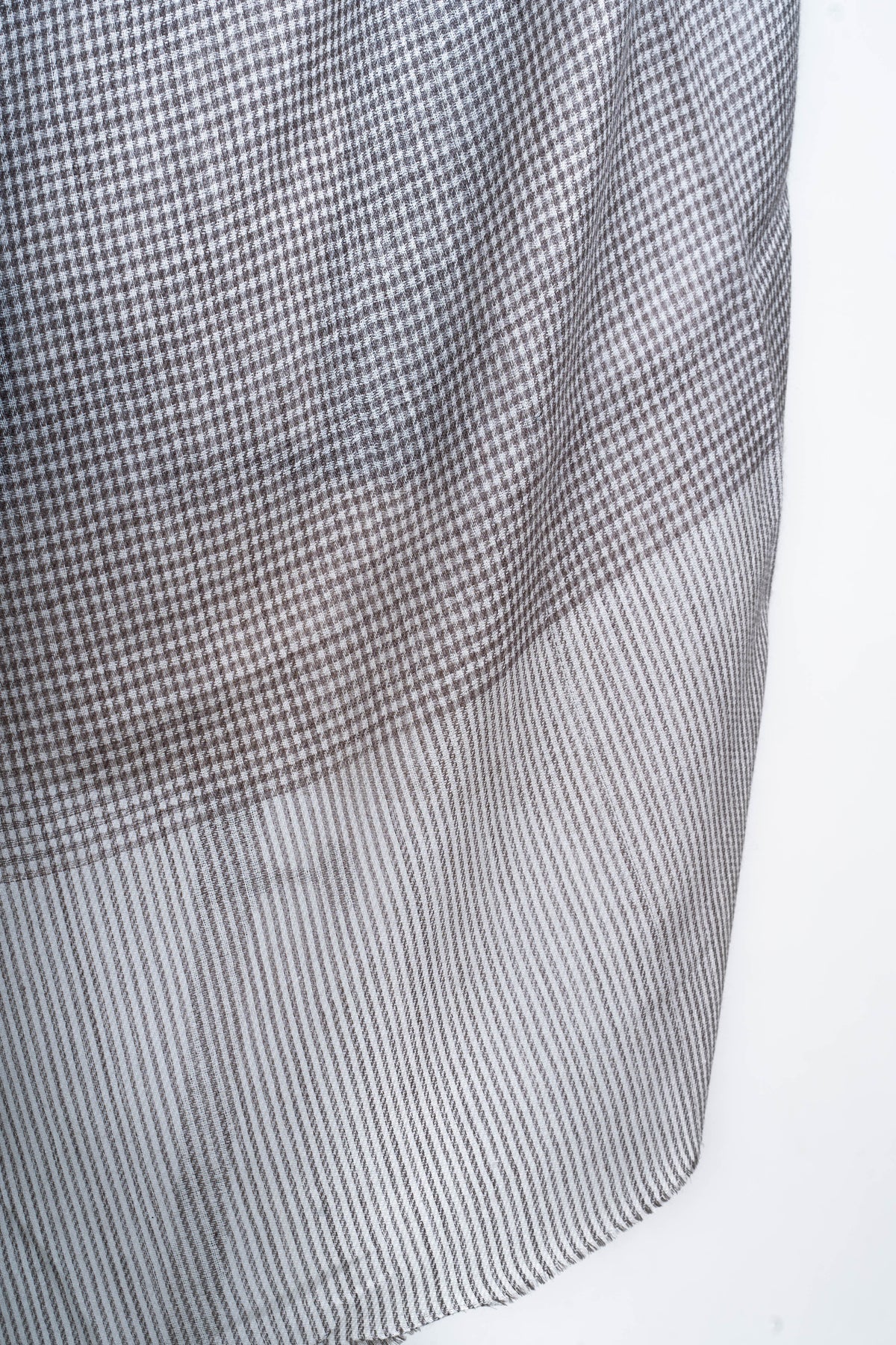 Close-up of the stole end where the fine charcoal checks meet a lighter panel of narrow stripes.
