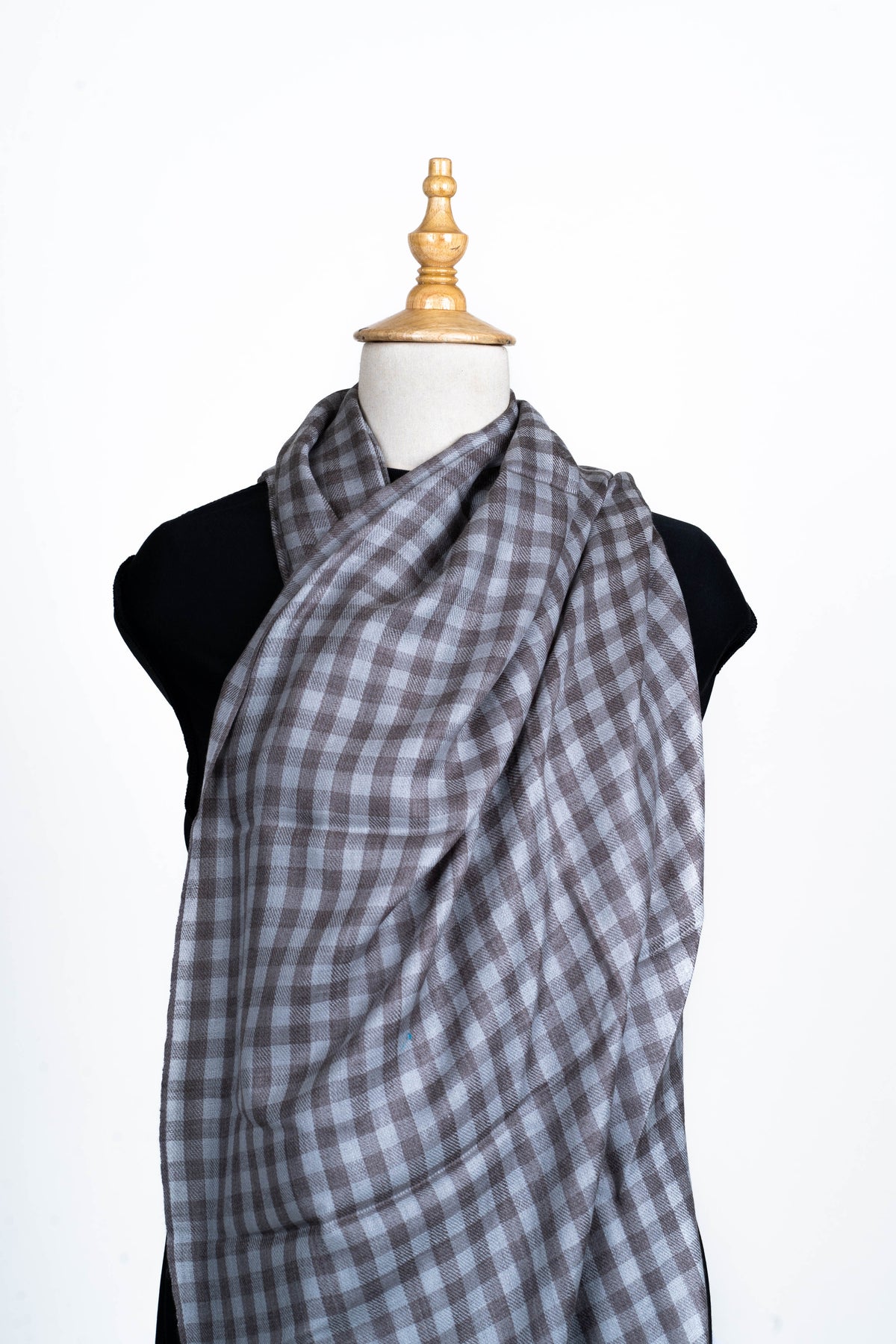 Grey checked stole wrapped broadly across a mannequin chest and over one shoulder.