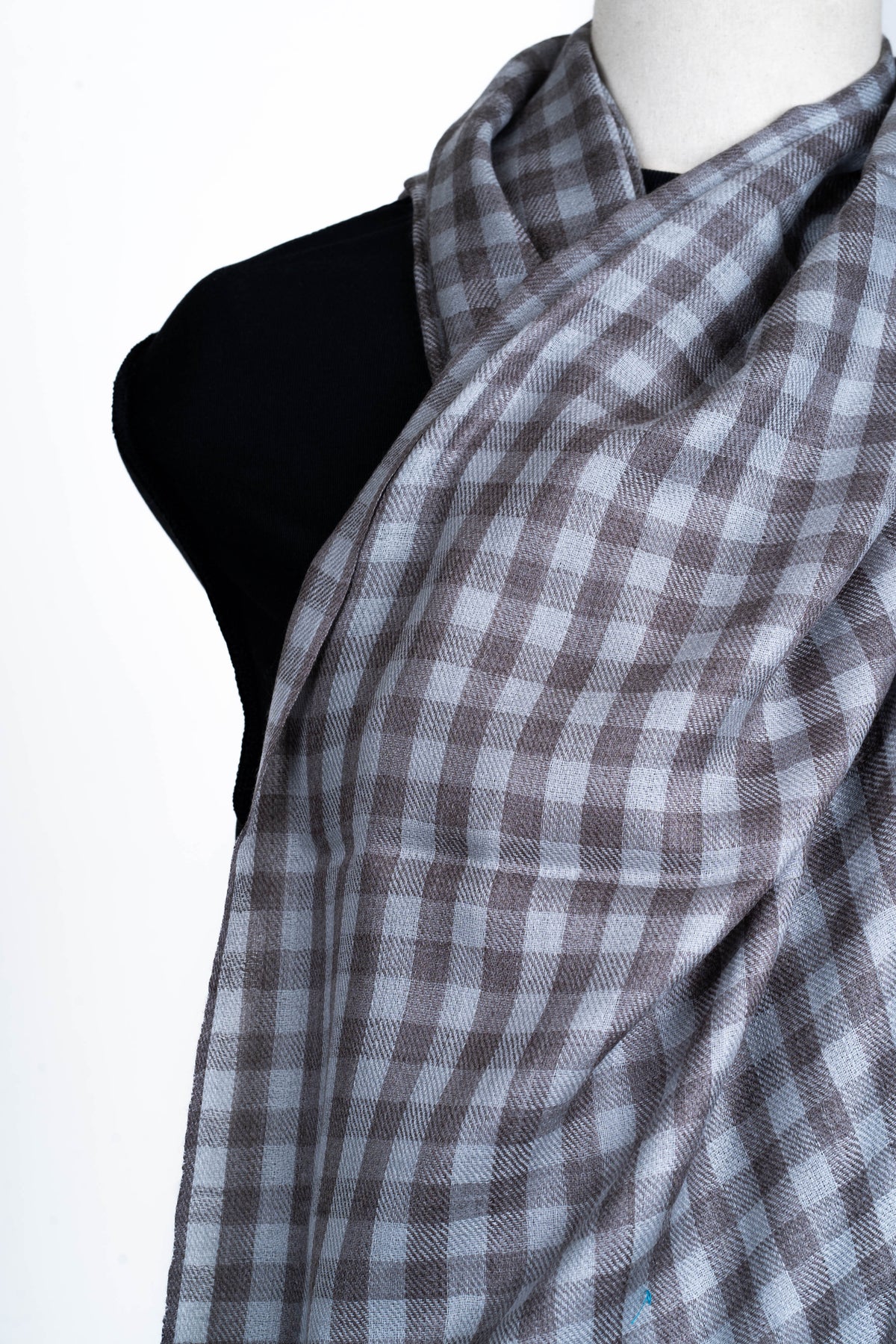 Close-up of steel-grey and charcoal checks across the softly folded stole on a mannequin chest.