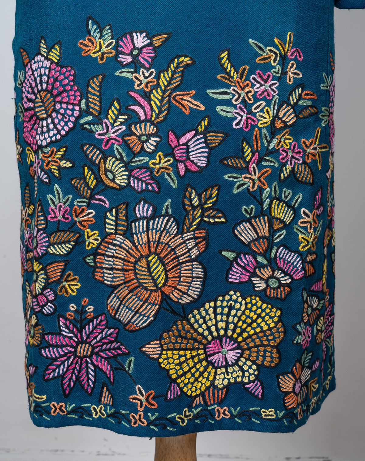 Lower front of a teal Merino wool pheran densely embroidered with large pink, yellow and orange flowers and leafy stems