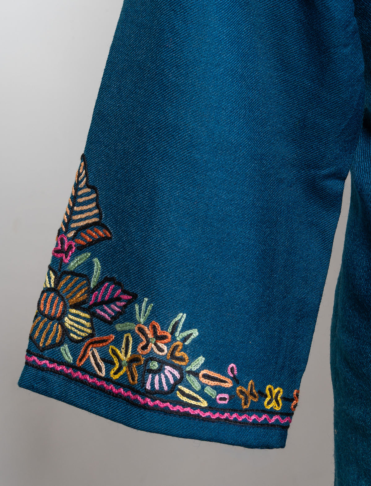 Teal pheran sleeve cuff with colourful Sozni flowers and leaves above a narrow pink embroidered edge