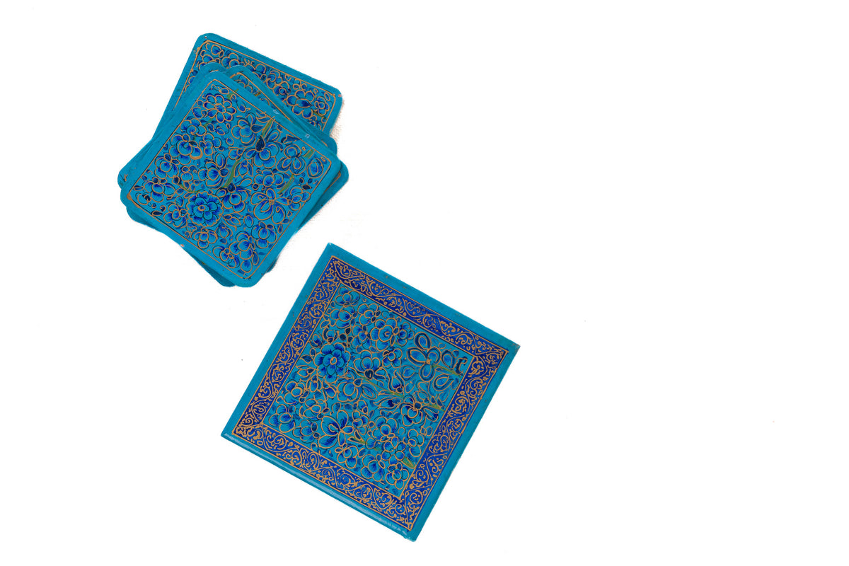 Blue floral coasters stacked at an angle beside a matching box with a narrow ornamental border
