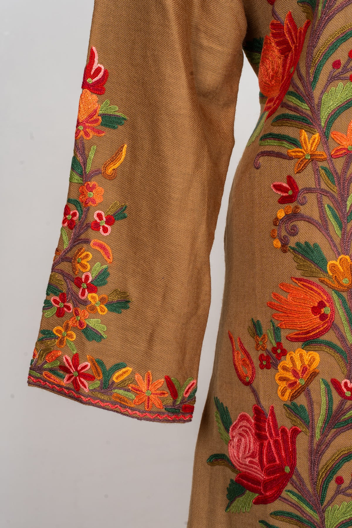 Sleeve and cuff detail of the earthy brown Hand Aari jacket, with red and orange flowers and green leaves