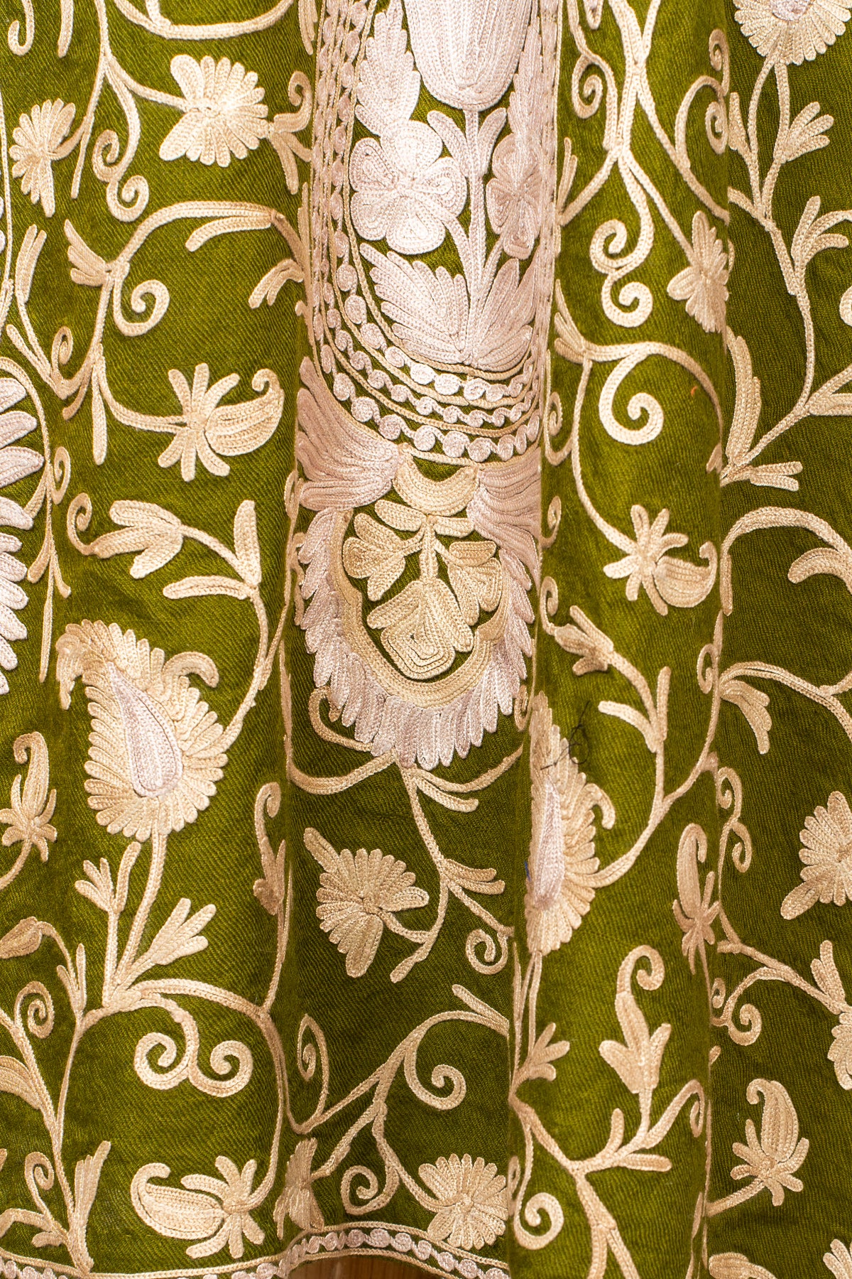 Detail of pale beige floral vines and a large ornamental paisley motif on the olive green abaya