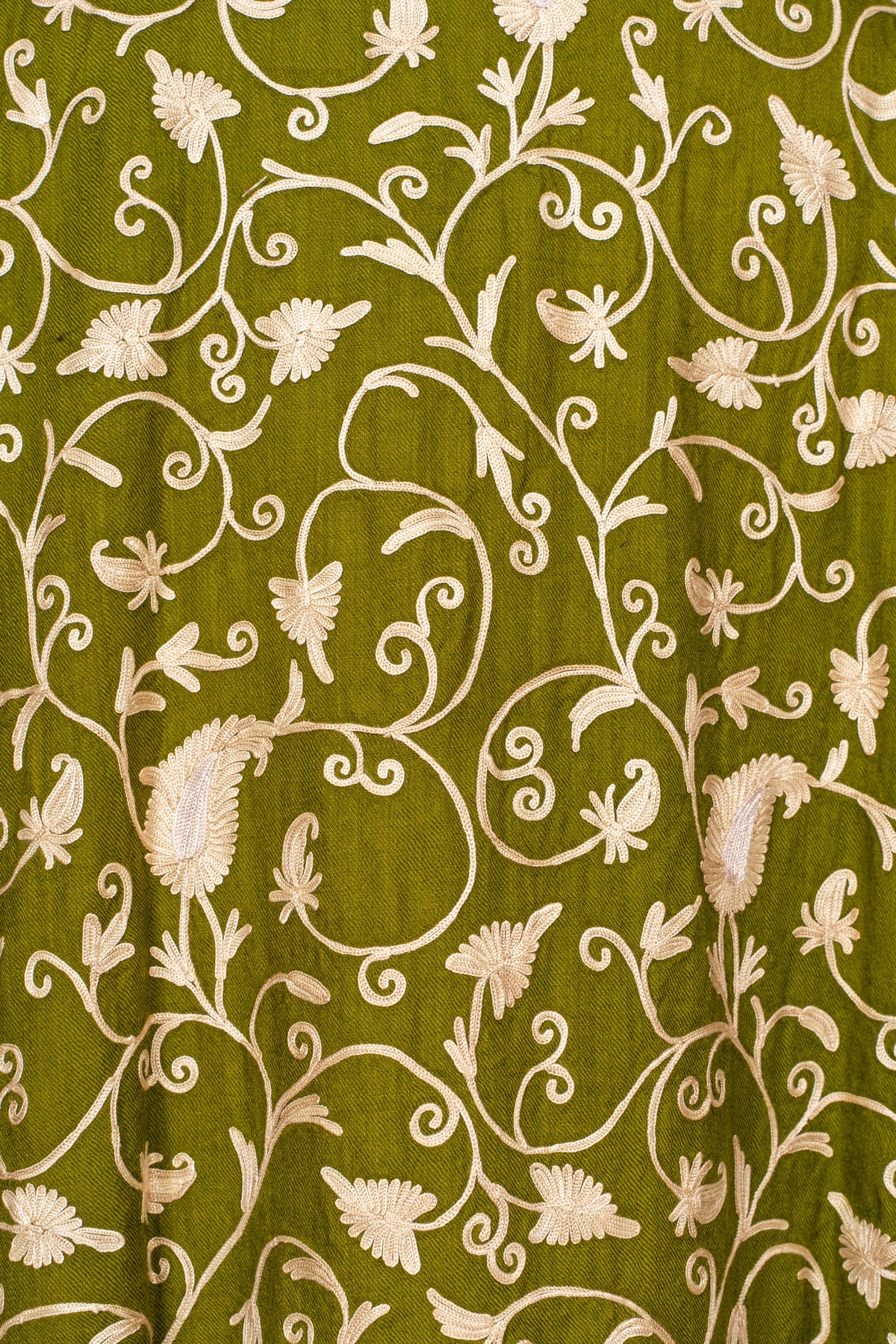 Detail of pale beige flowers, leaves and scrolling stems embroidered across the olive green abaya